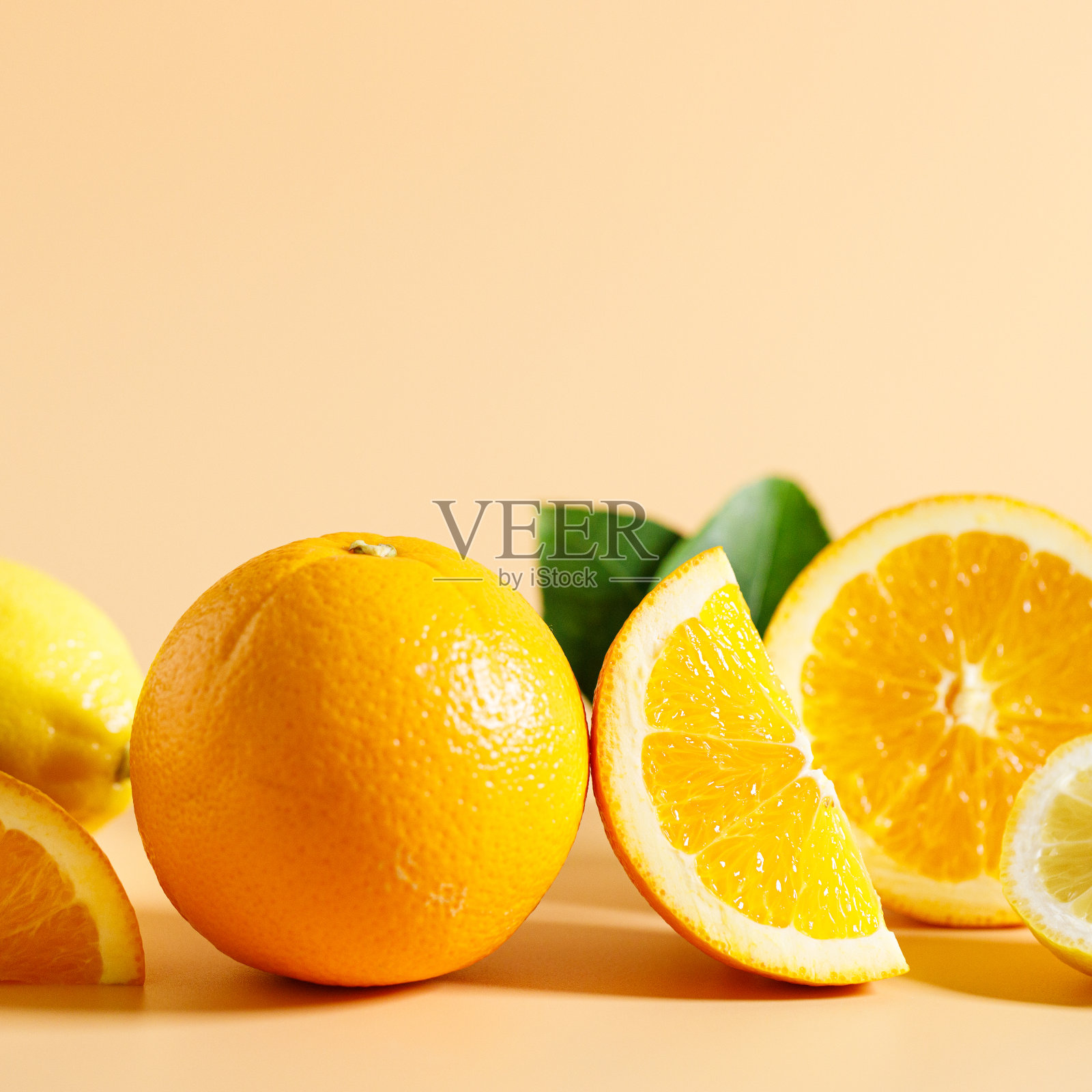 整个和切开的橙子和柠檬，带有绿色的叶子，橙色的背景照片摄影图片