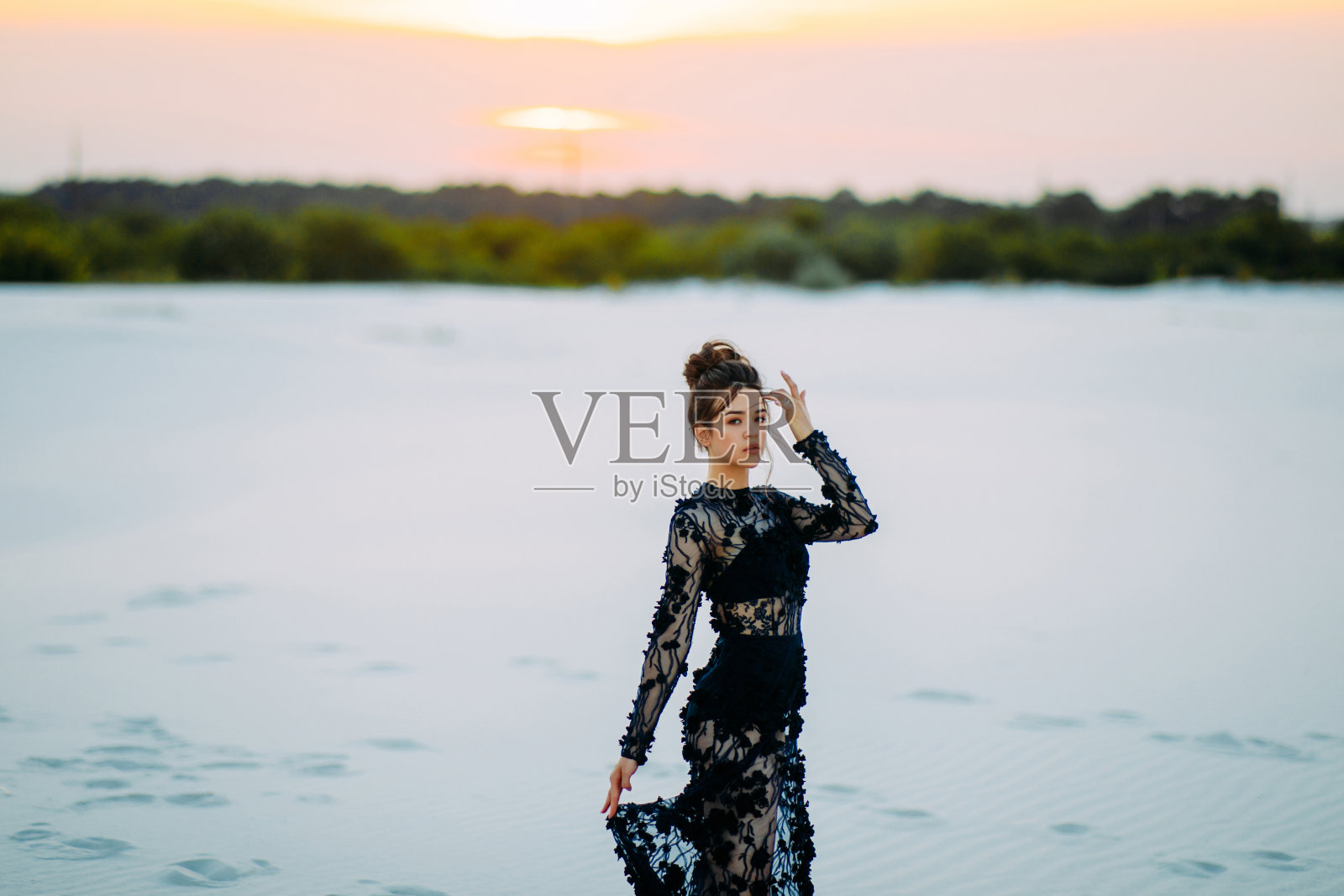 日落时分，一名女子站在沙漠中拍照留影。照片摄影图片