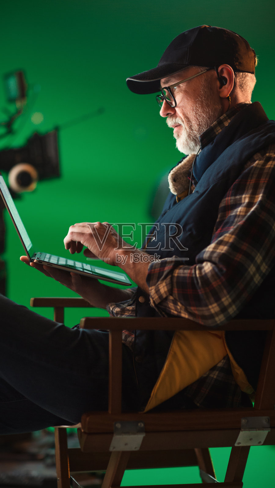 杰出的成功导演坐在椅子上休息，使用笔记本电脑。在工作室电影设置与高端设备专业人员拍摄高预算电影照片摄影图片