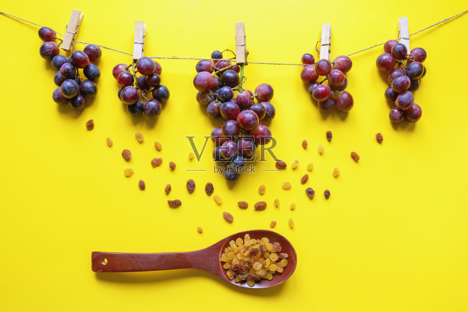 秋天的概念。绳子上别着一串串葡萄，木勺里装着葡萄干照片摄影图片