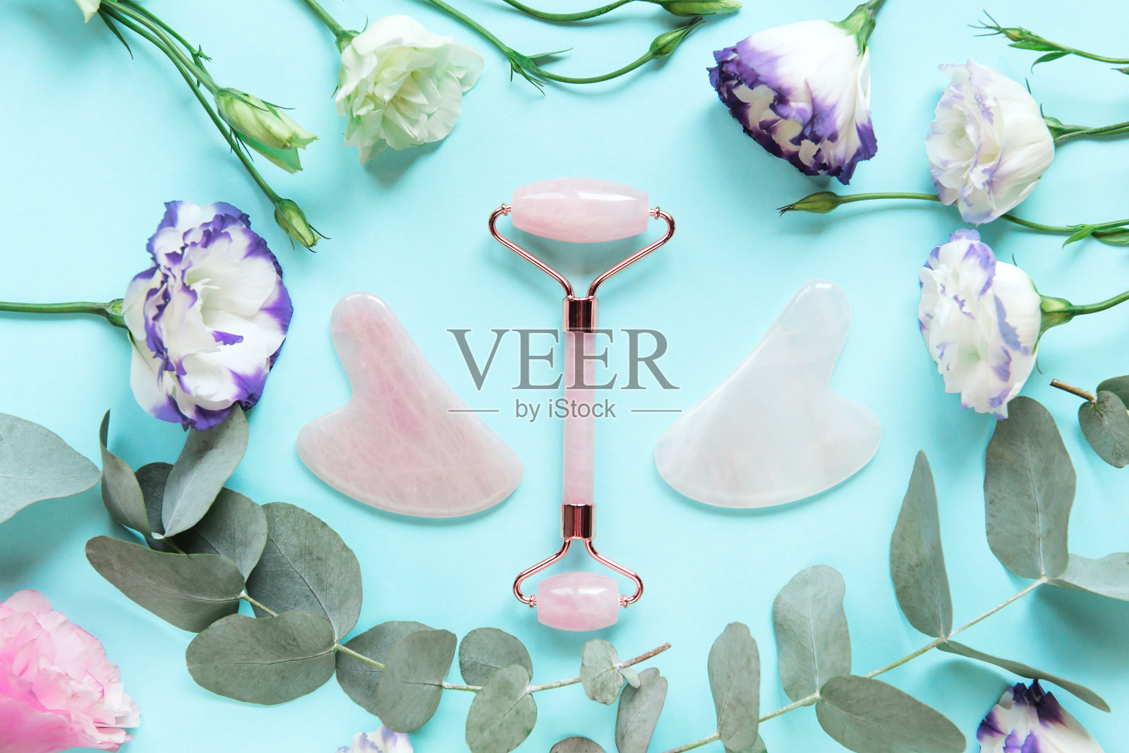 家庭水疗面部按摩包。面辊由玫瑰石英和瓜沙按摩器在柔和的蓝色背景照片摄影图片