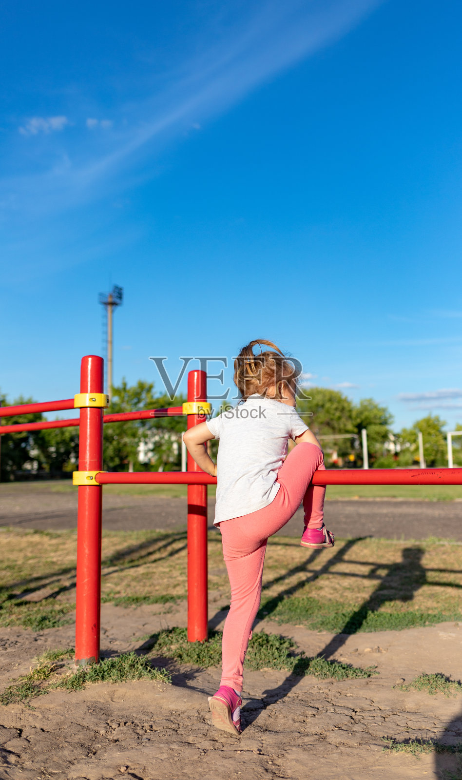 一个小孩在公园里做运动。挂在单杠上，高低杠上照片摄影图片