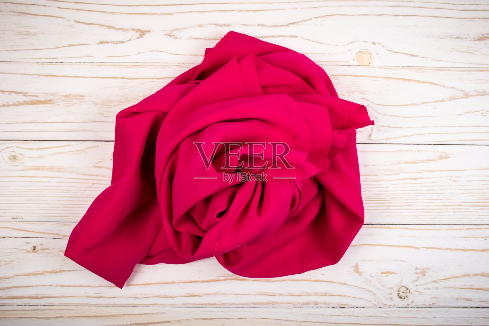 白色木板上的一块粉红色或玫瑰色的纺织品或织物照片摄影图片