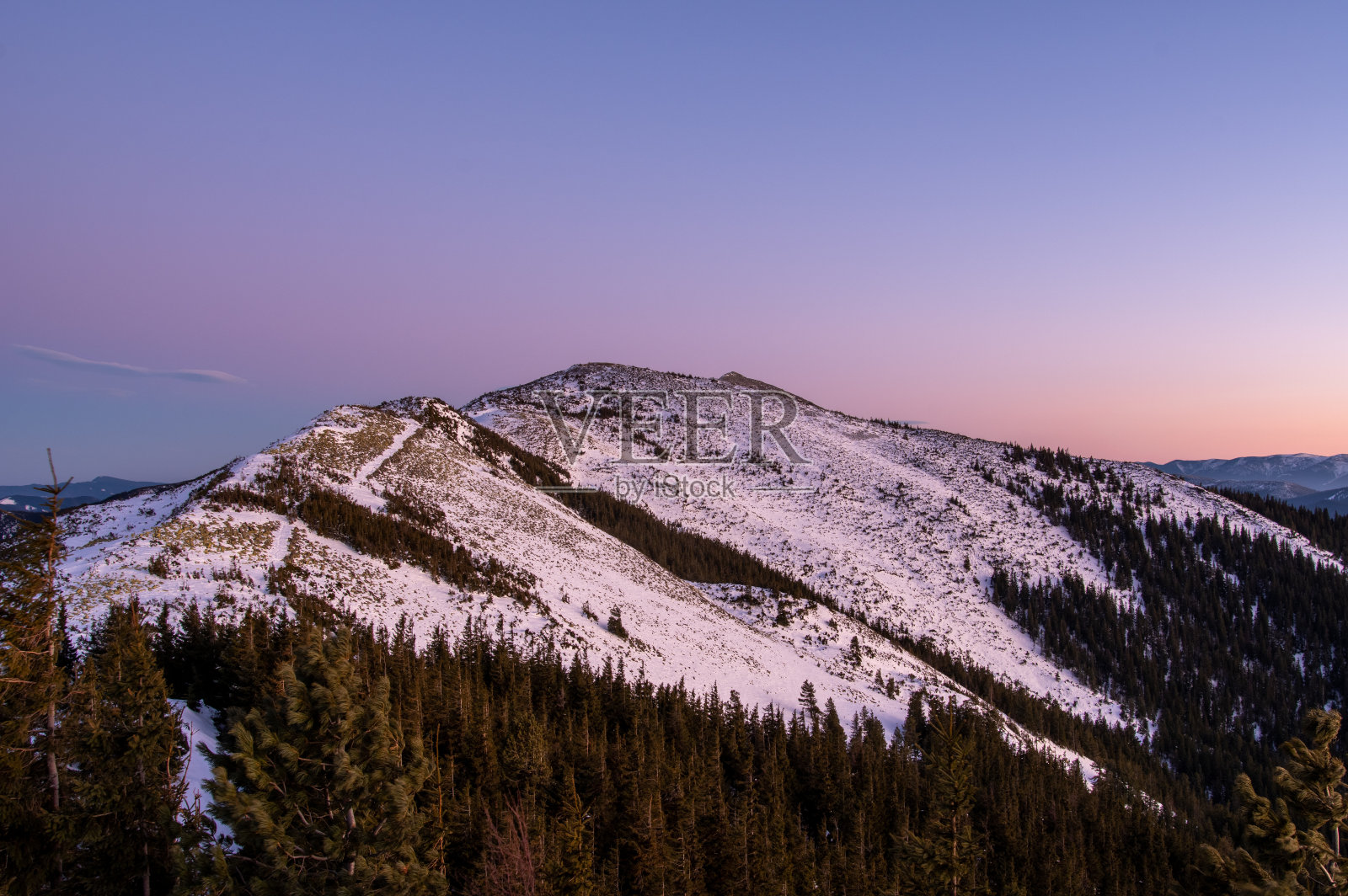 白雪覆盖的大山脉。夕阳下的雪山。美丽的冬季山地景观。照片摄影图片