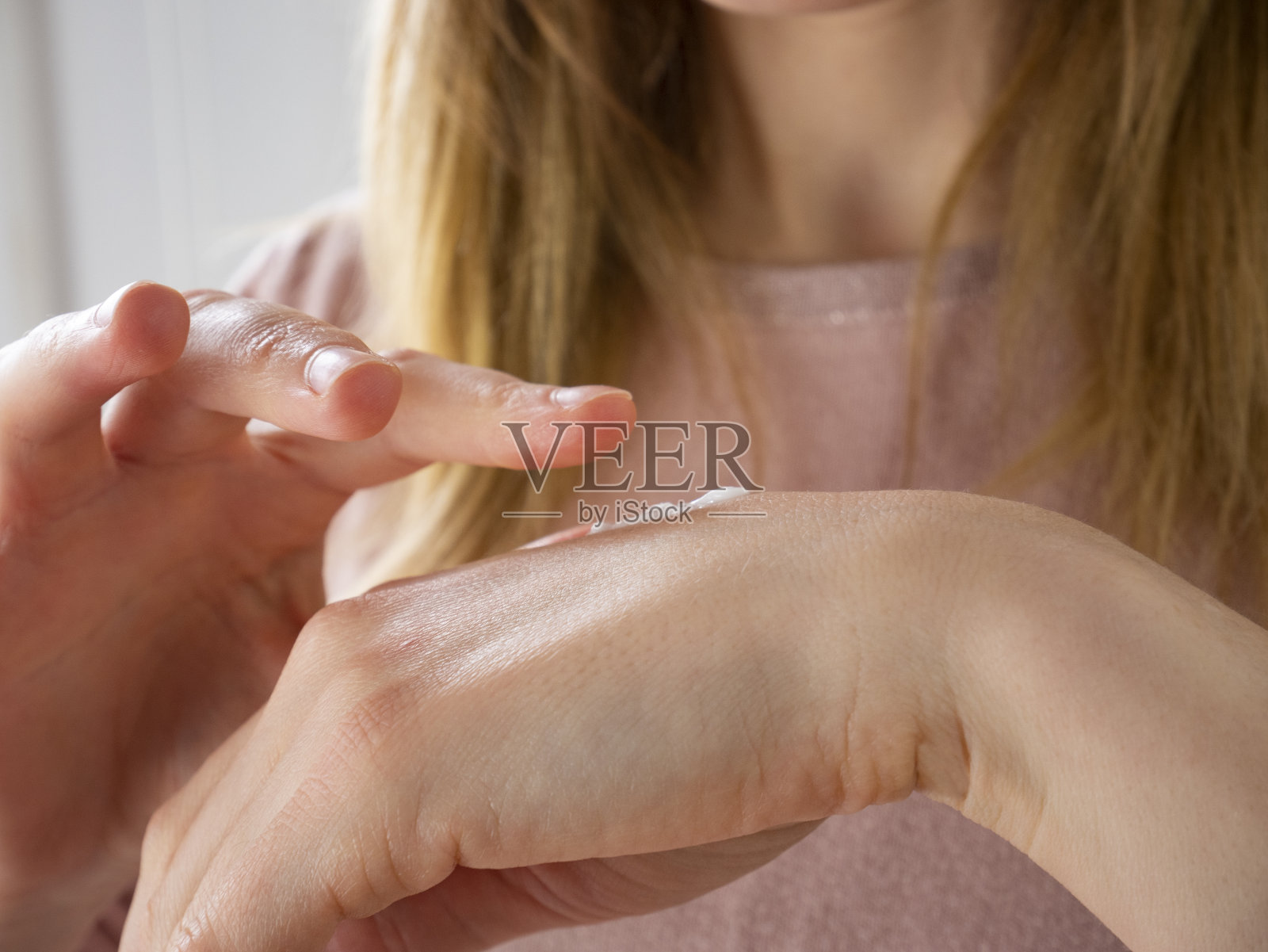 年轻女子在手上涂抹护手霜，护肤产品照片摄影图片