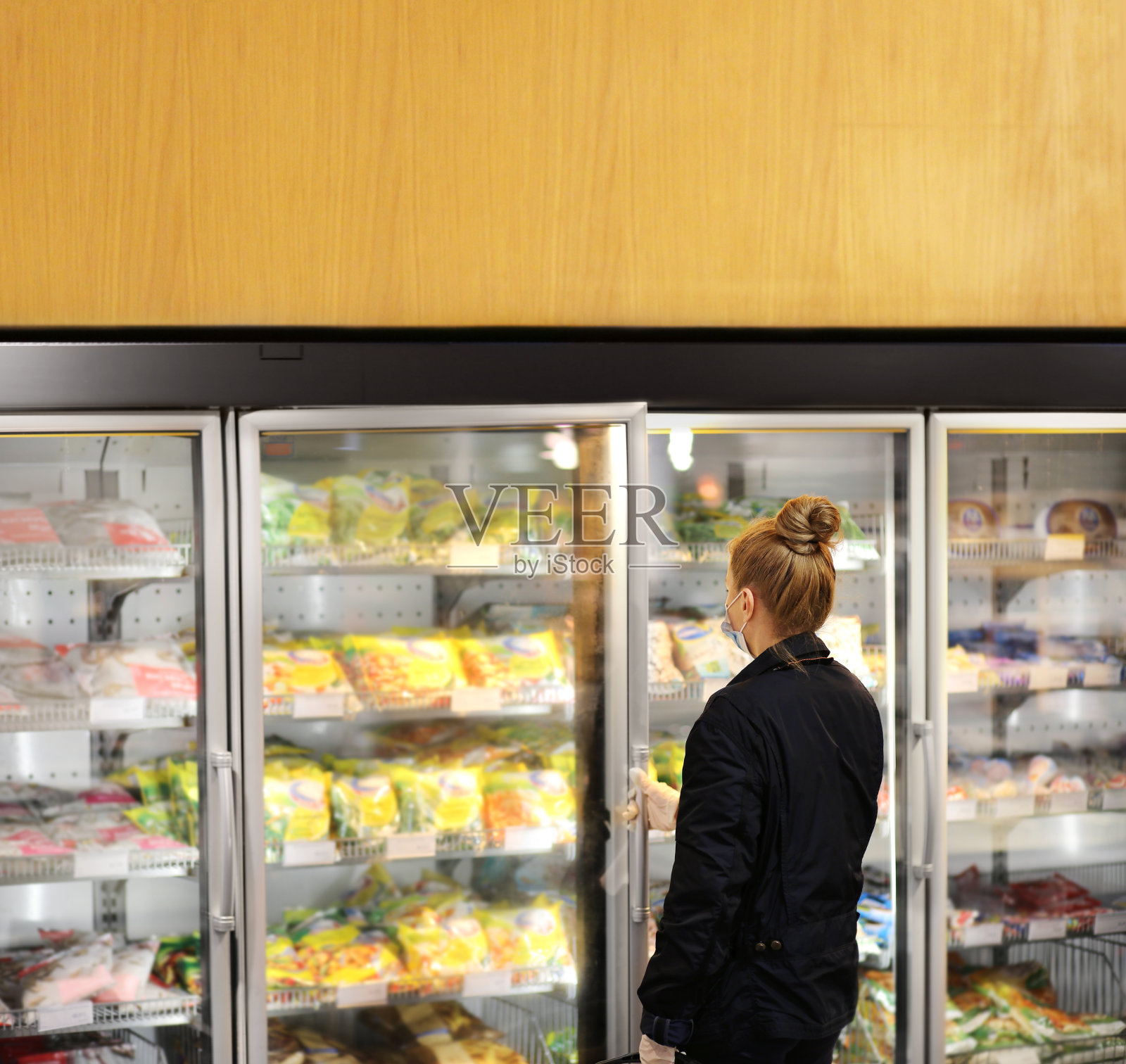 超市购物，口罩和手套，从超市冰箱中选择冷冻食品的女人照片摄影图片