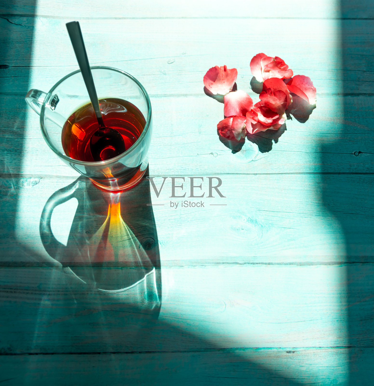 一杯茶和蓝色木质背景上的玫瑰花瓣。俯视图照片摄影图片