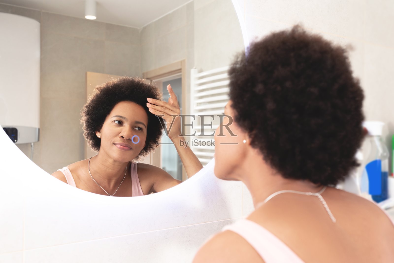 在家对着镜子看头发的女人照片摄影图片