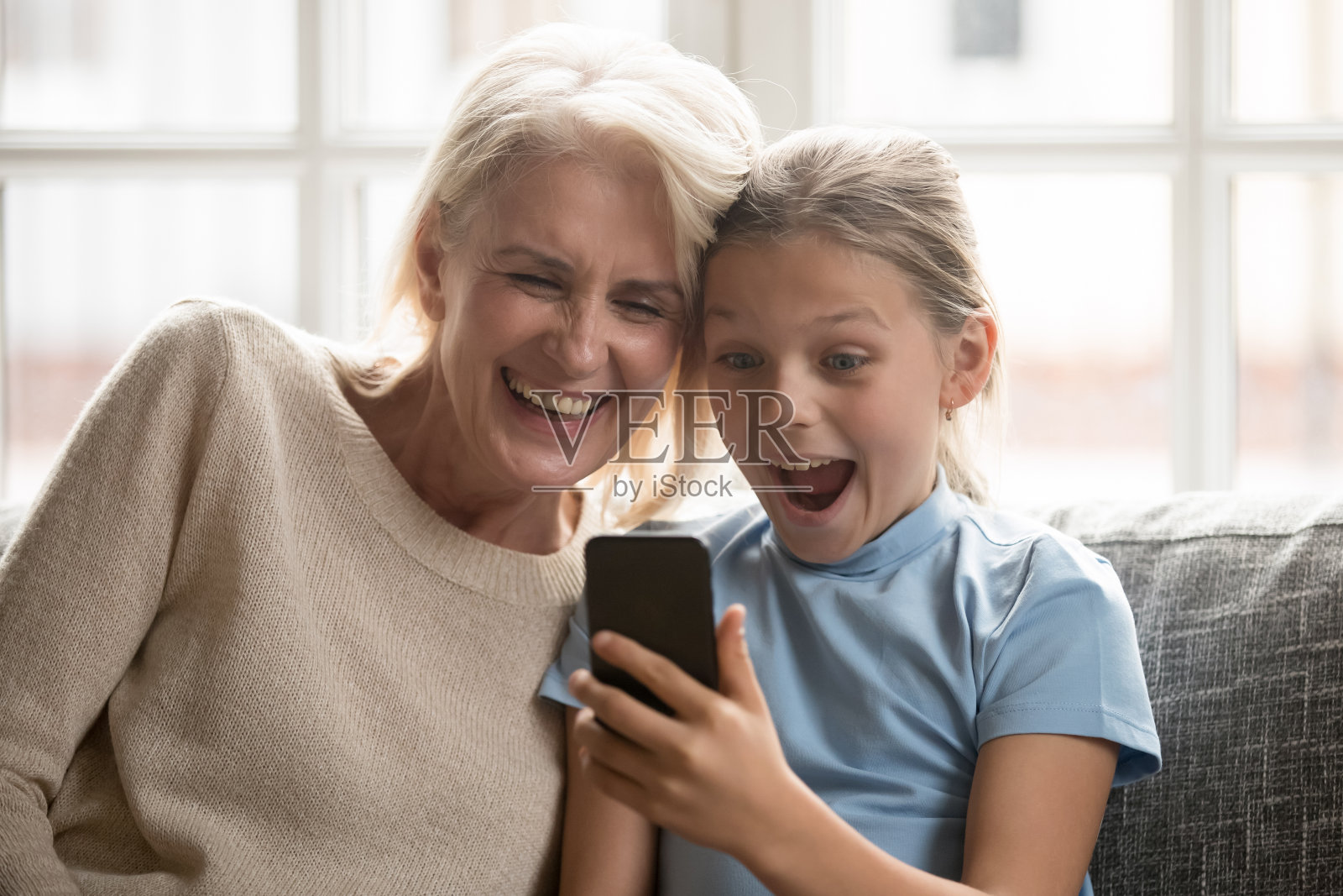 兴奋的祖母和孙女在手机上看有趣的视频照片摄影图片