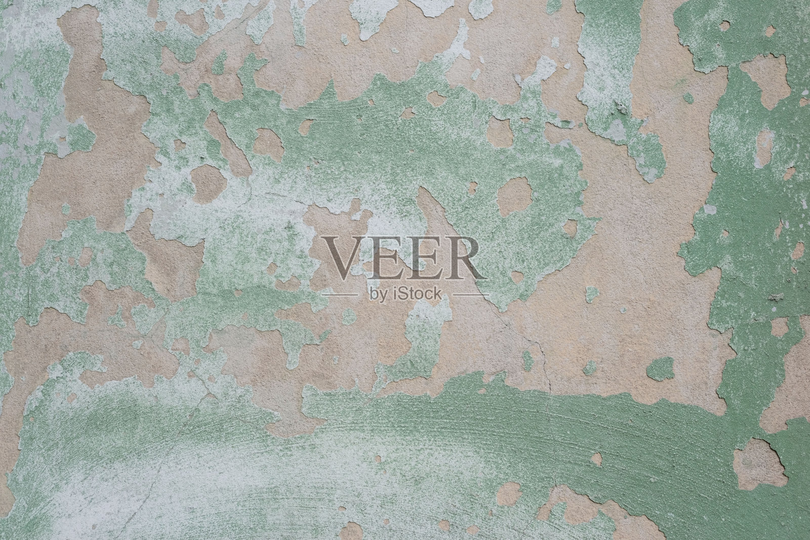 灰泥的纹理呈绿色，带有摩擦的灰色油漆的成分。有质感的街道墙的柔和色调。墙上有裂缝，旧的绿色灰泥上有很多洞照片摄影图片