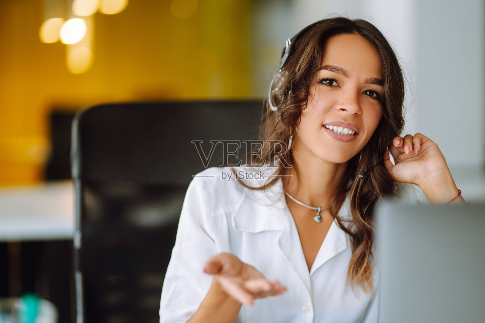 年轻的女话务员，戴着耳机在呼叫中心工作。照片摄影图片