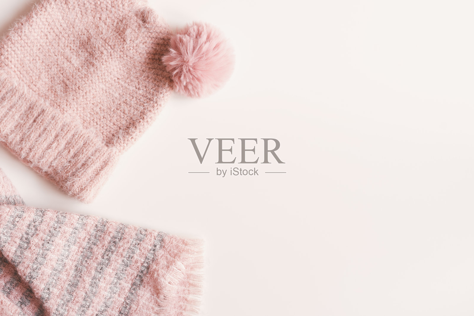 白色背景上的粉色手工针织帽子和围巾，顶部视图，留有复制空间。保暖服装概念照片摄影图片