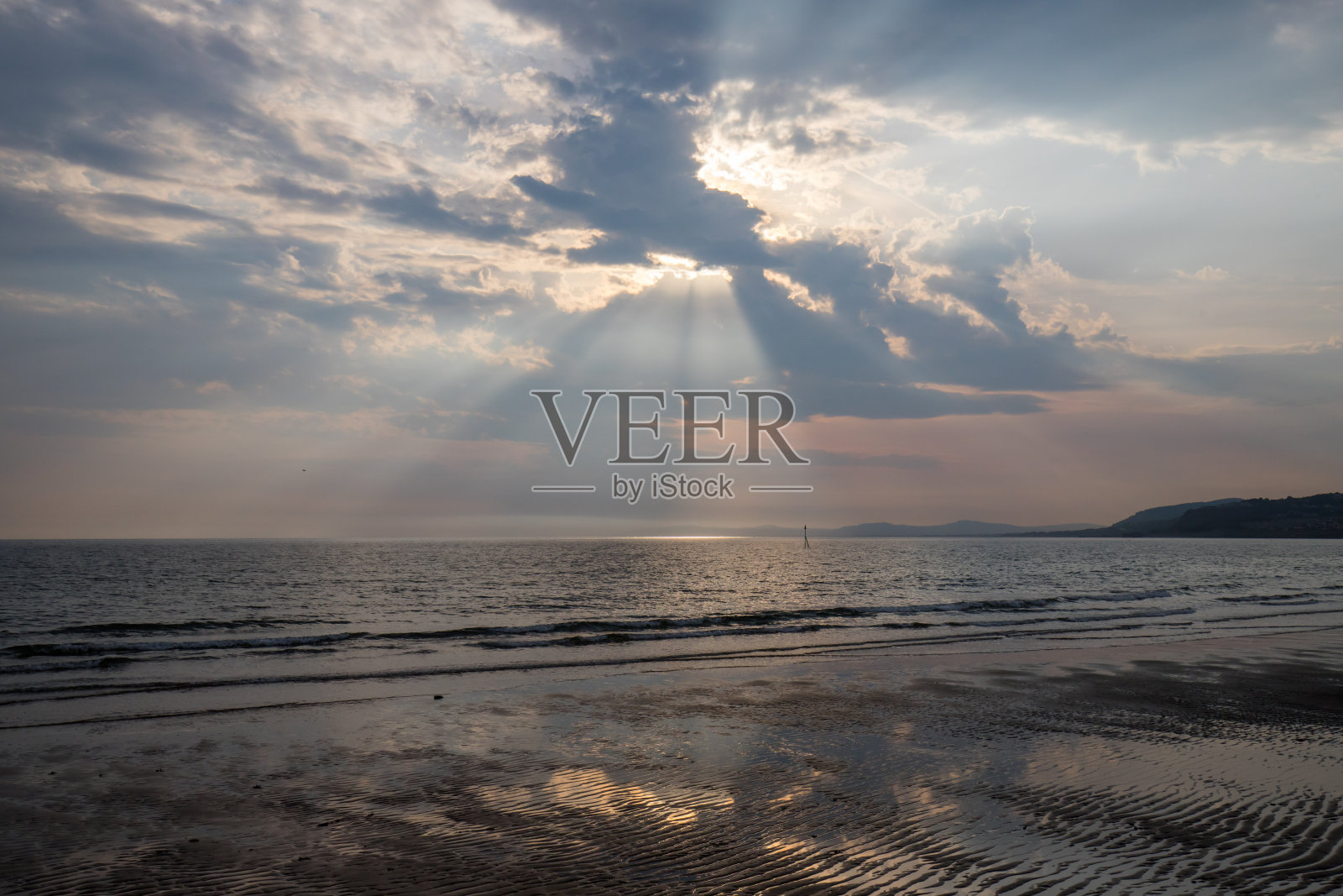 北威尔士科尔温湾上空阳光灿烂的天空。黎明时分，海岸上出现了平静的海面照片摄影图片