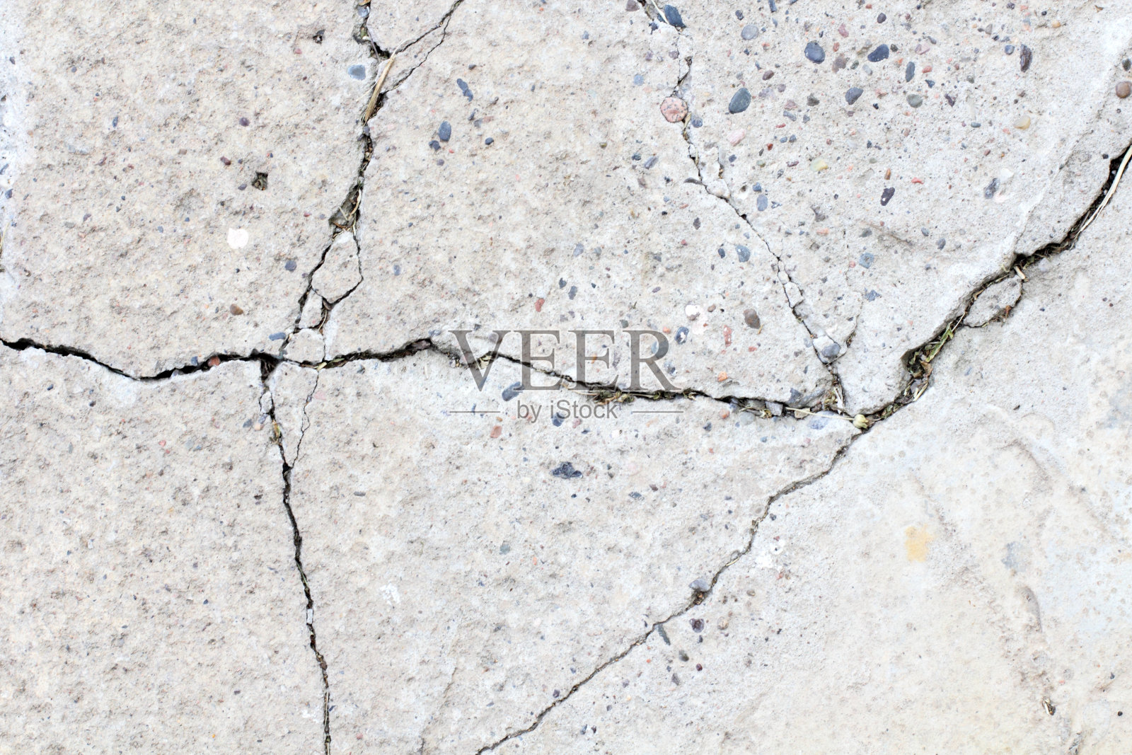 混凝土表面有裂缝，但没有涂漆，以不同大小的鹅卵石作为背景照片摄影图片