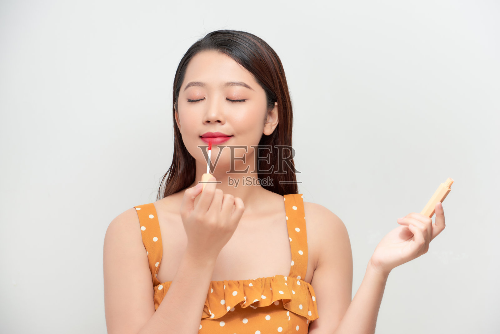 可爱的女孩在涂唇彩。面部表情，美容照片摄影图片