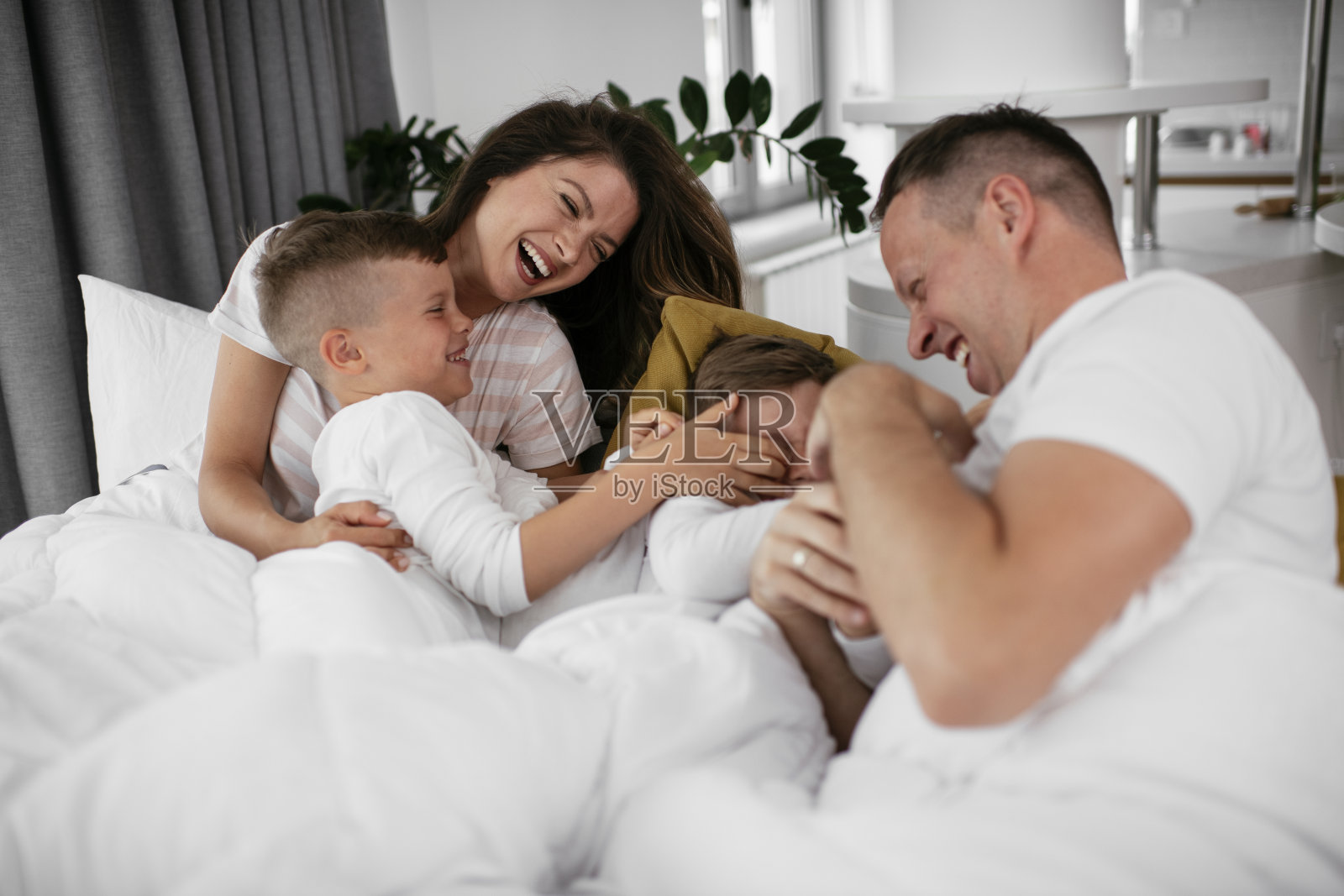 年轻的家庭享受在床上。照片摄影图片