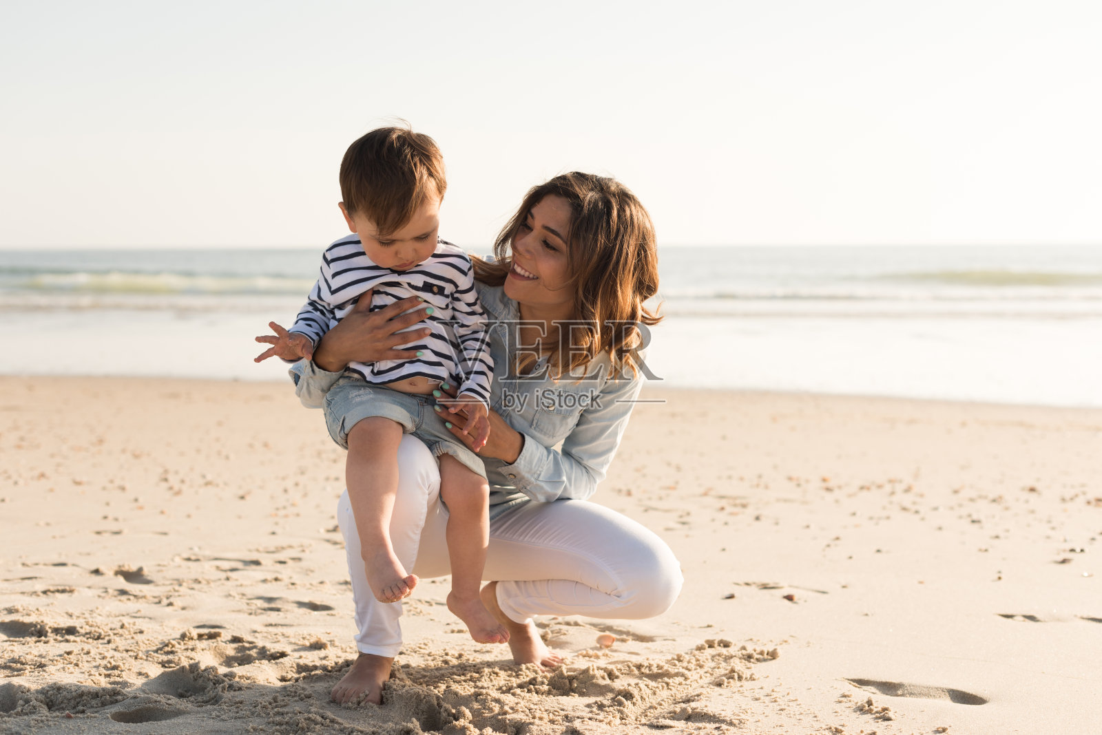 妈妈和她的孩子在海滩上照片摄影图片