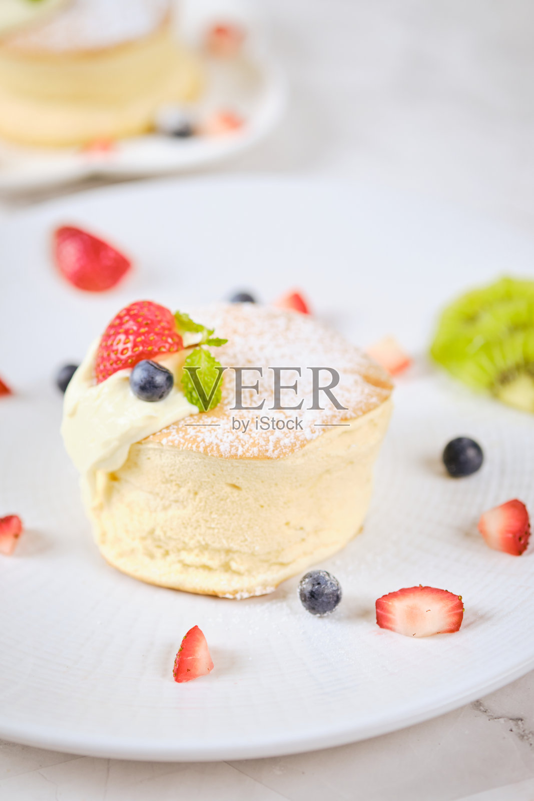 白盘子里有奶油和浆果的松软蛋奶酥煎饼。照片摄影图片