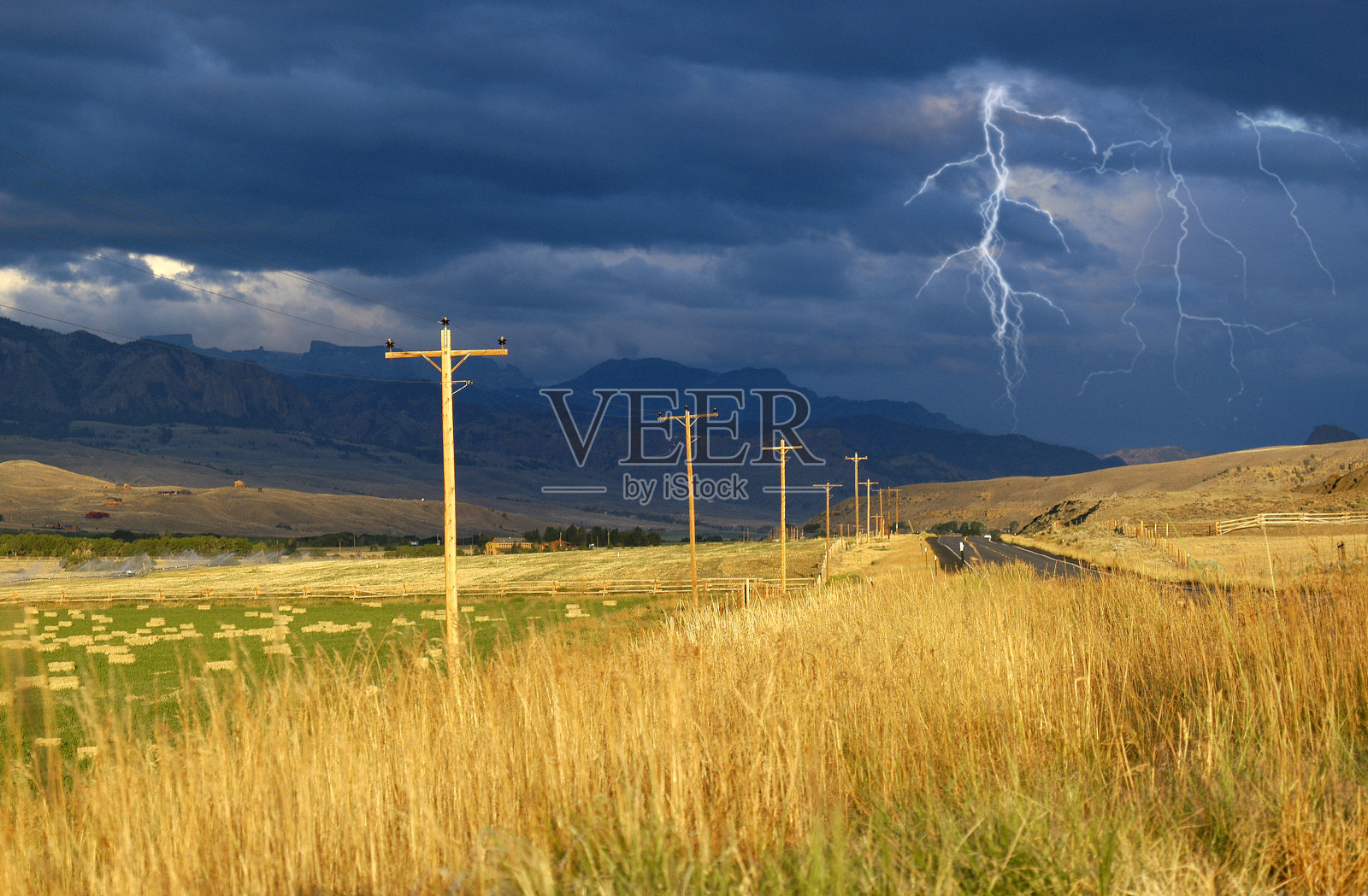 在有闪电和大雨的暴风雨中开车，而留下阳光灿烂的天空，把干草变成黄金。照片摄影图片