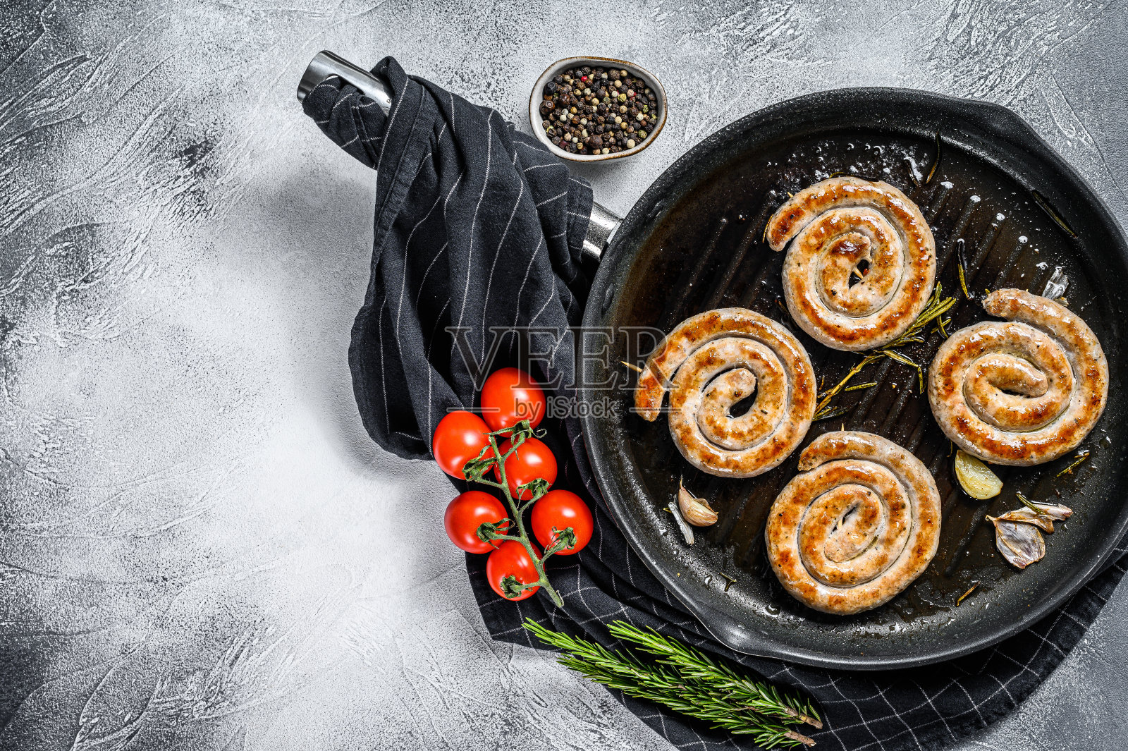 螺旋烤香肠与蔬菜在平底锅。灰色的背景。前视图。本空间照片摄影图片