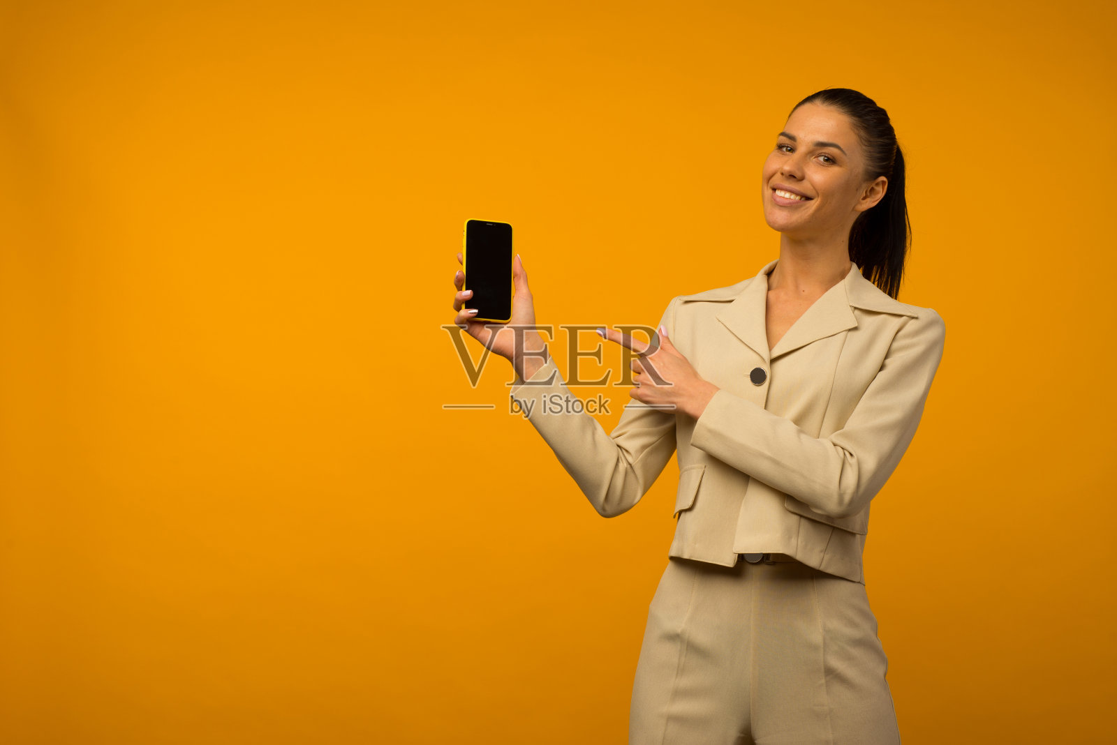 有面部皮肤问题的年轻女孩用黄色背景的智能手机拍照照片摄影图片