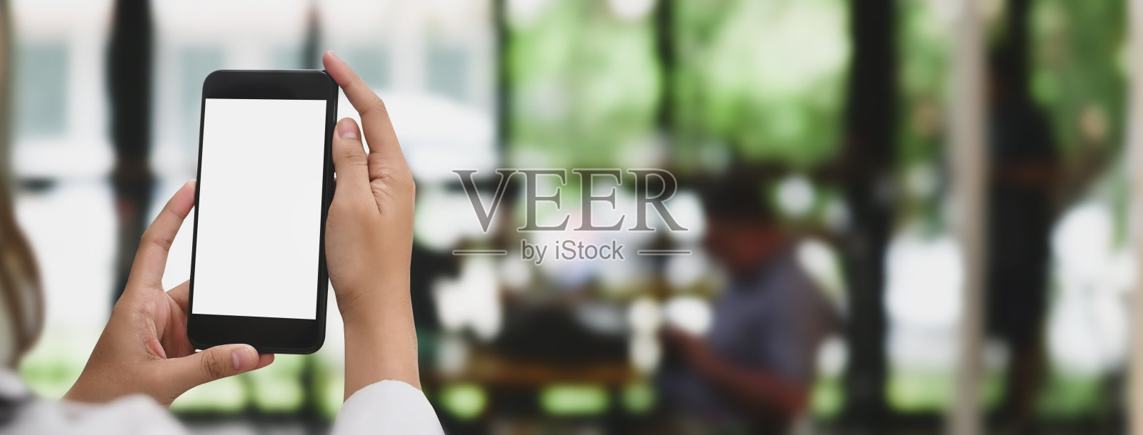 裁剪图像的手使用一个白色的空白屏幕的手机与一个餐馆作为背景。照片摄影图片