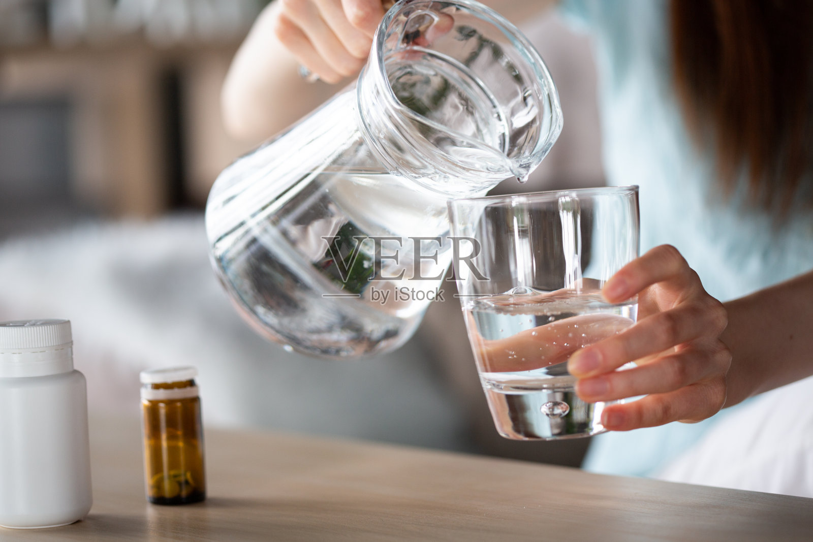 妇女把水从罐子倒进玻璃杯里，服用补品照片摄影图片
