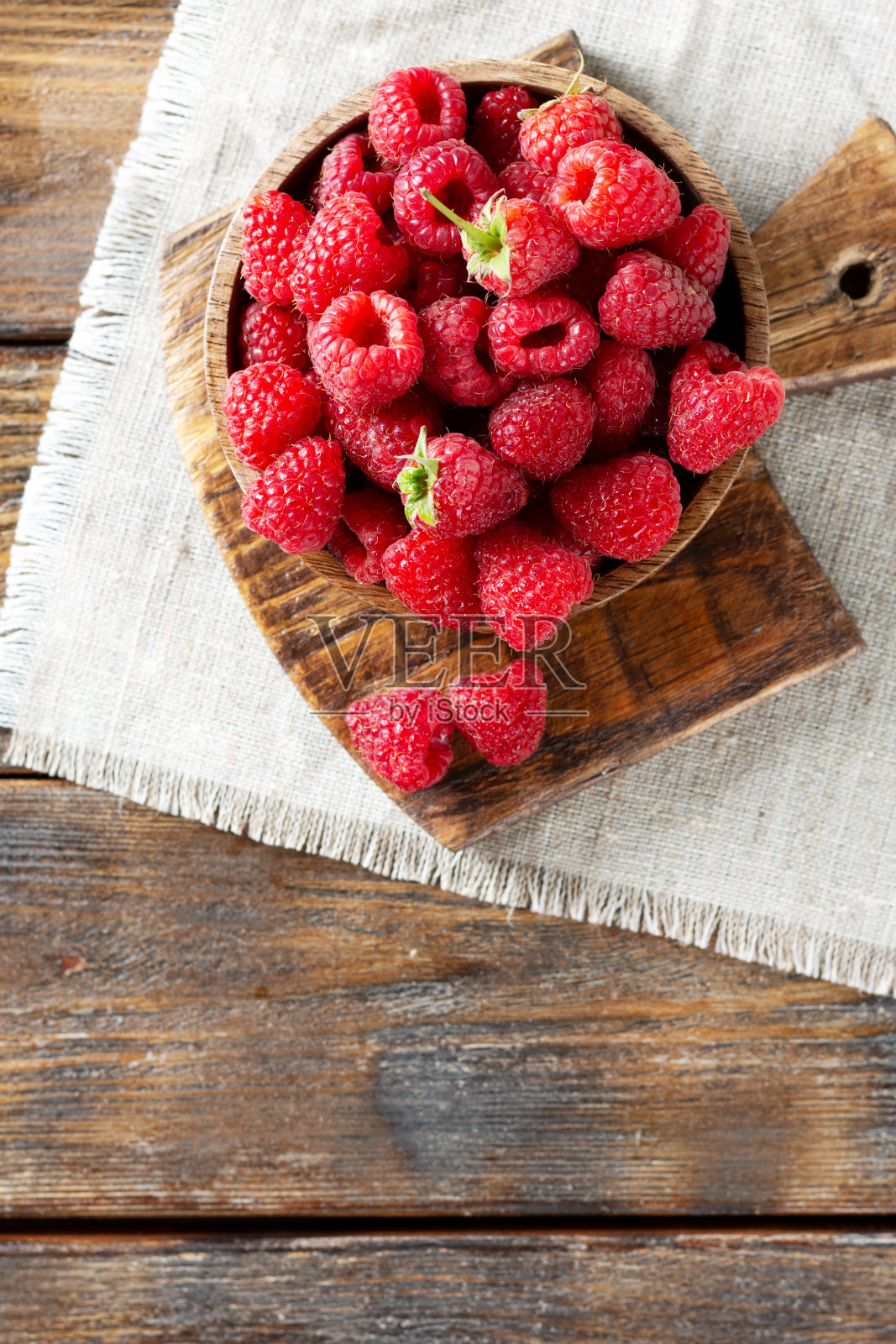 木碗里的覆盆子放在棕色的木桌上。树莓浆果特写。新鲜的覆盆子放在盘子里。空间的文本。健康的饮食习惯照片摄影图片