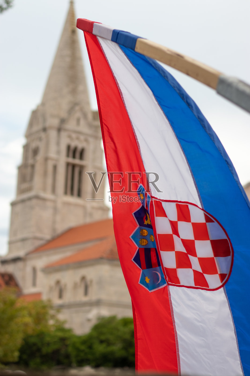 克罗地亚国旗在风中飘扬的特写，背景是克罗地亚塞尔卡村的教堂。庆祝克罗地亚独立战争的胜利照片摄影图片