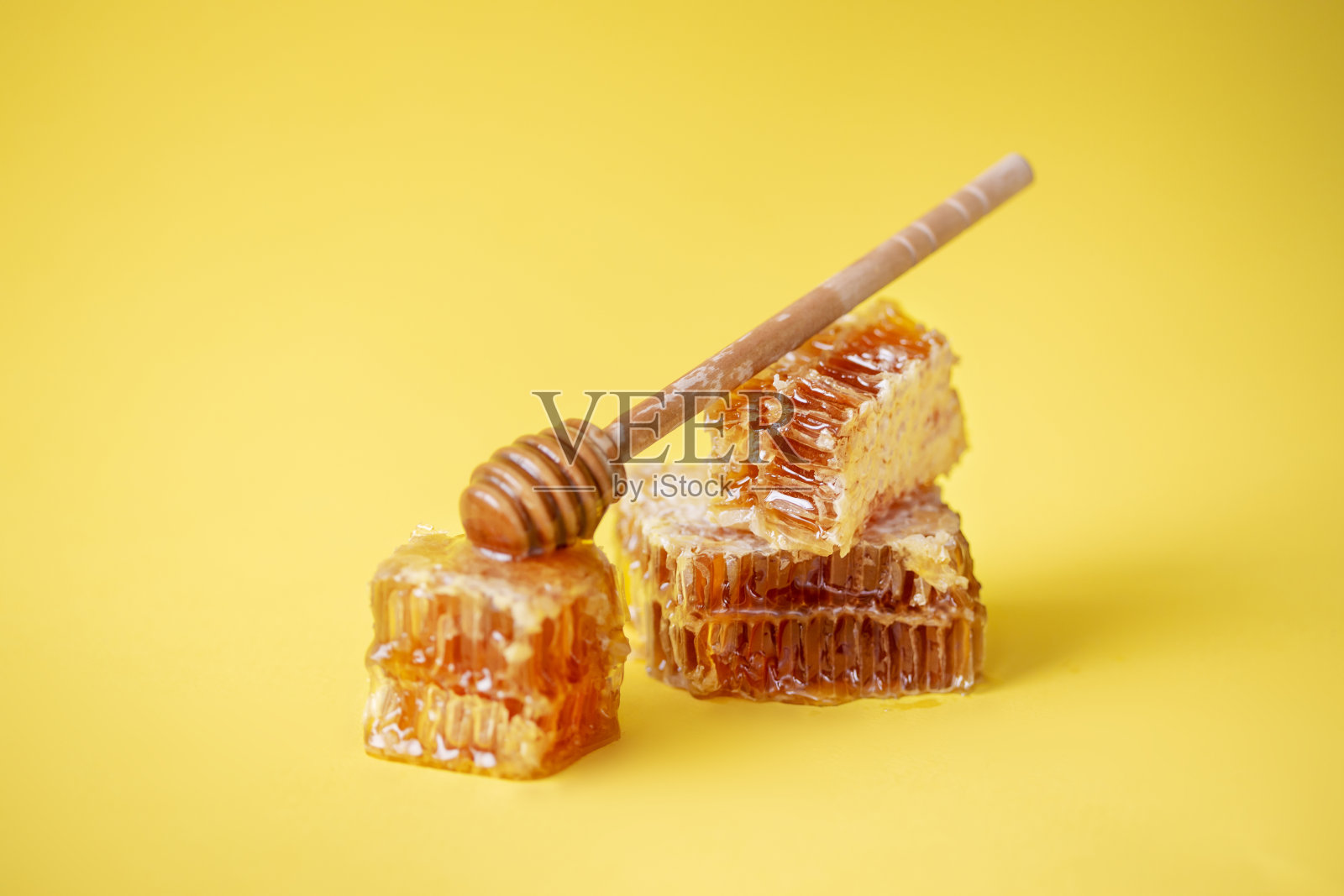 黄色背景上有木棒的蜂巢照片摄影图片