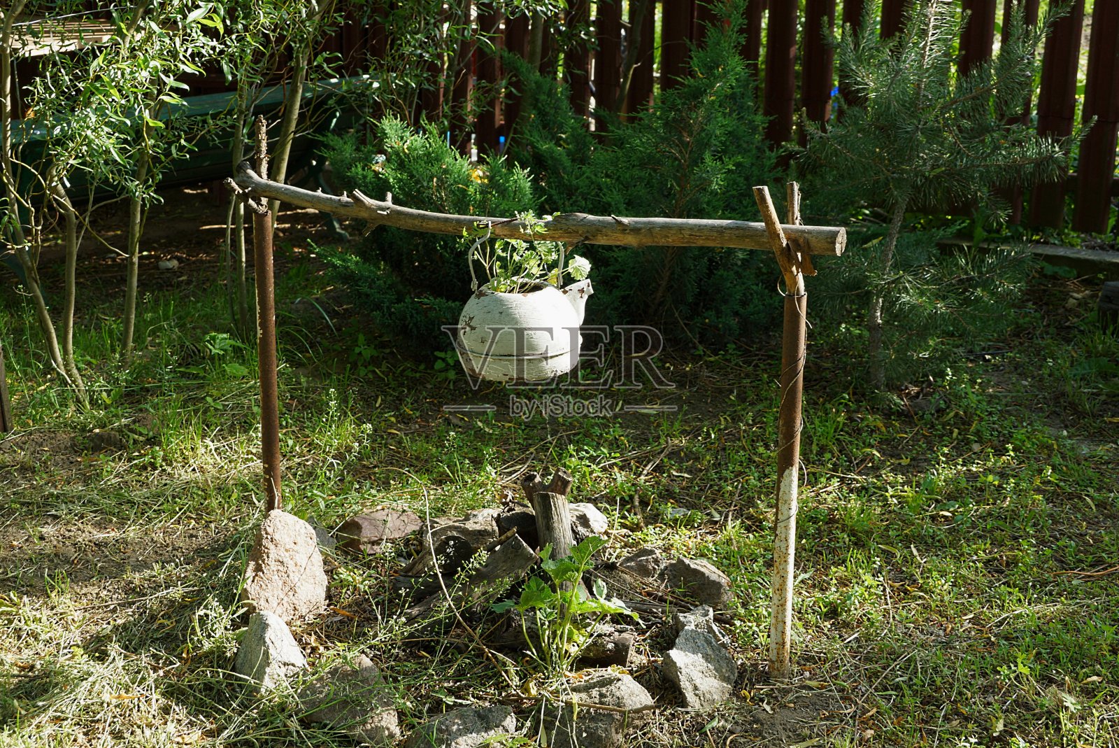 白色的旧金属茶壶，在一个装饰篝火上的木棍照片摄影图片