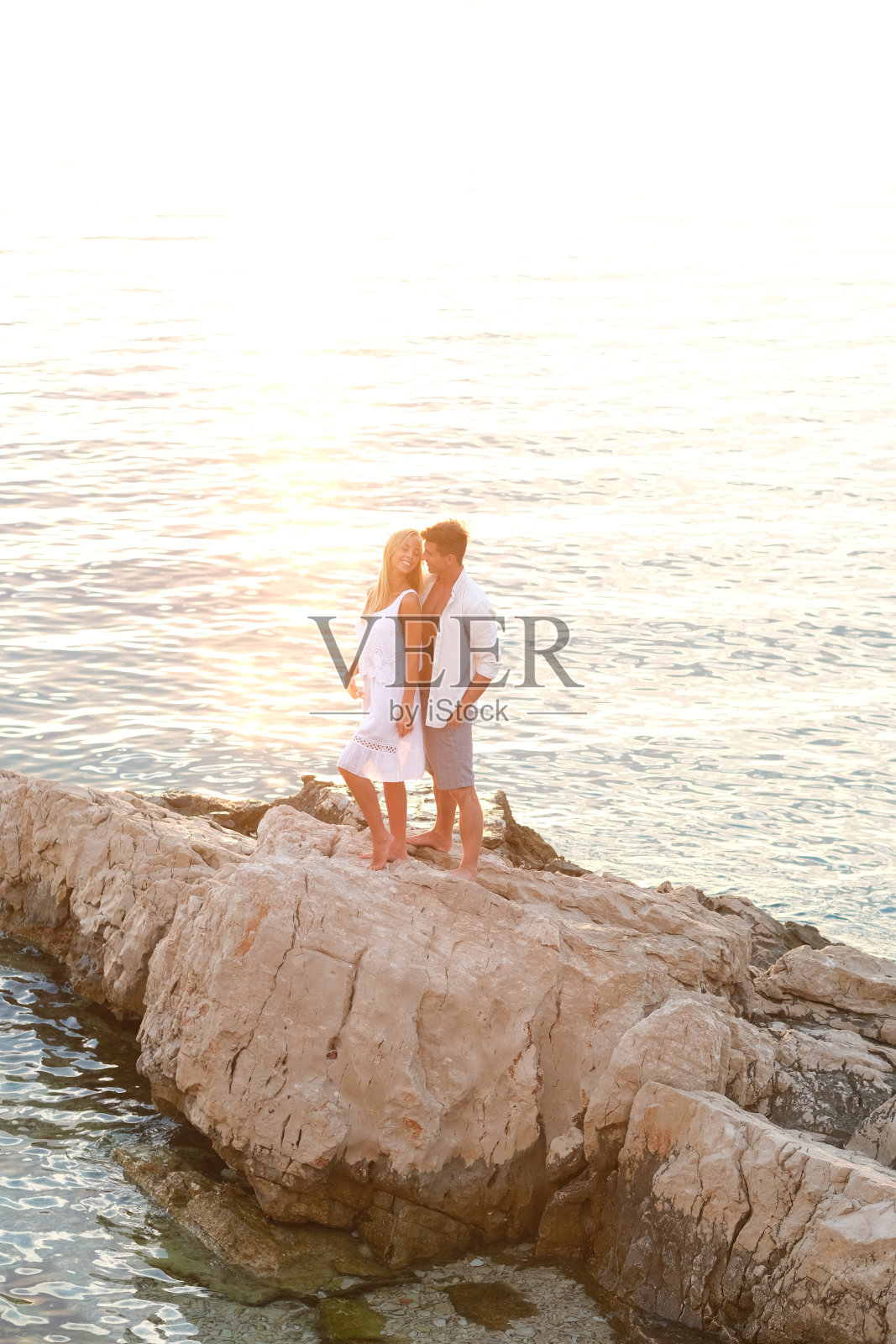 非常浪漫的时刻。年轻的夫妇，夕阳和大海。照片摄影图片