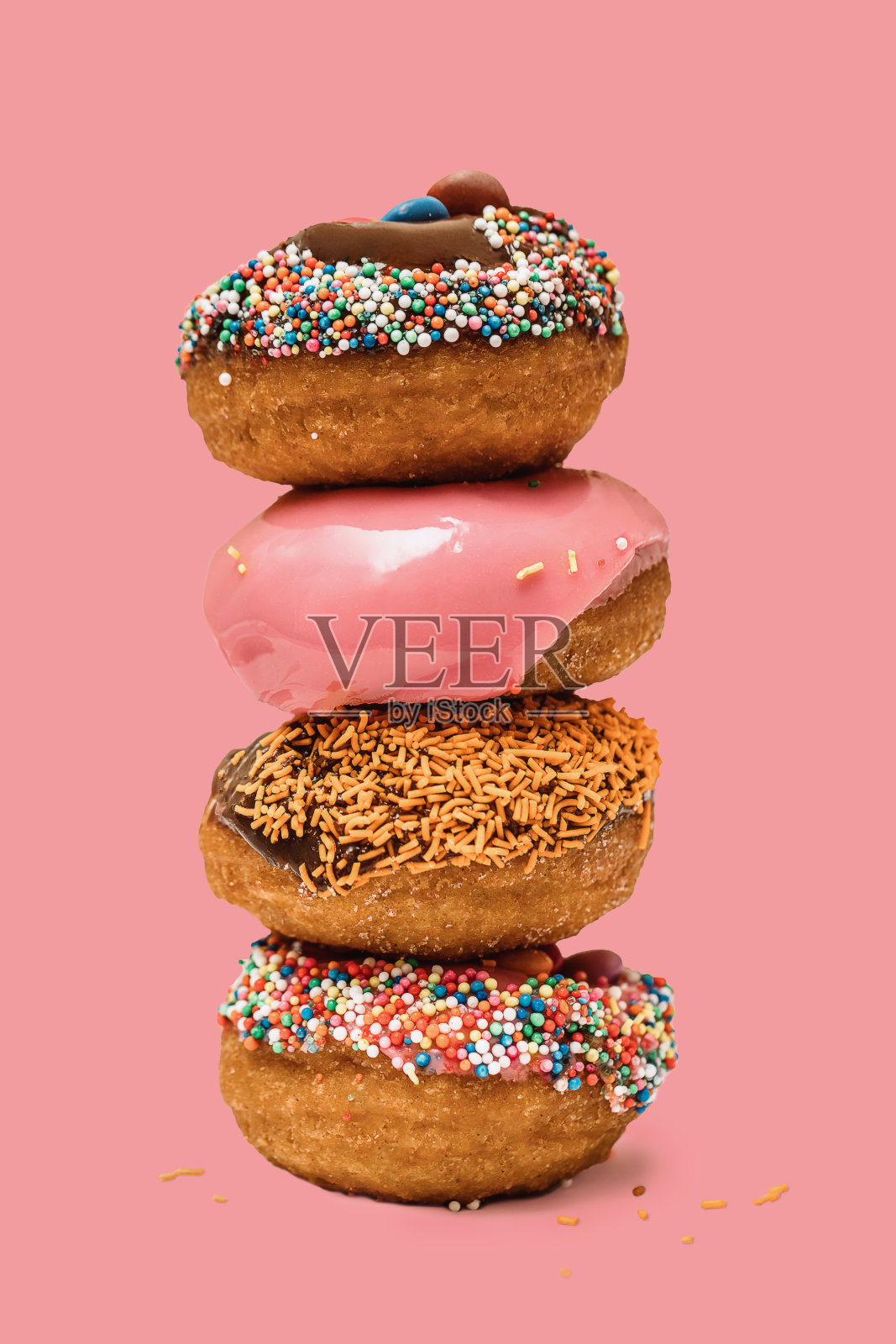 一个甜甜圈一个甜甜圈，粉红色的背景是糖霜和巧克力。可爱的甜甜圈照片摄影图片