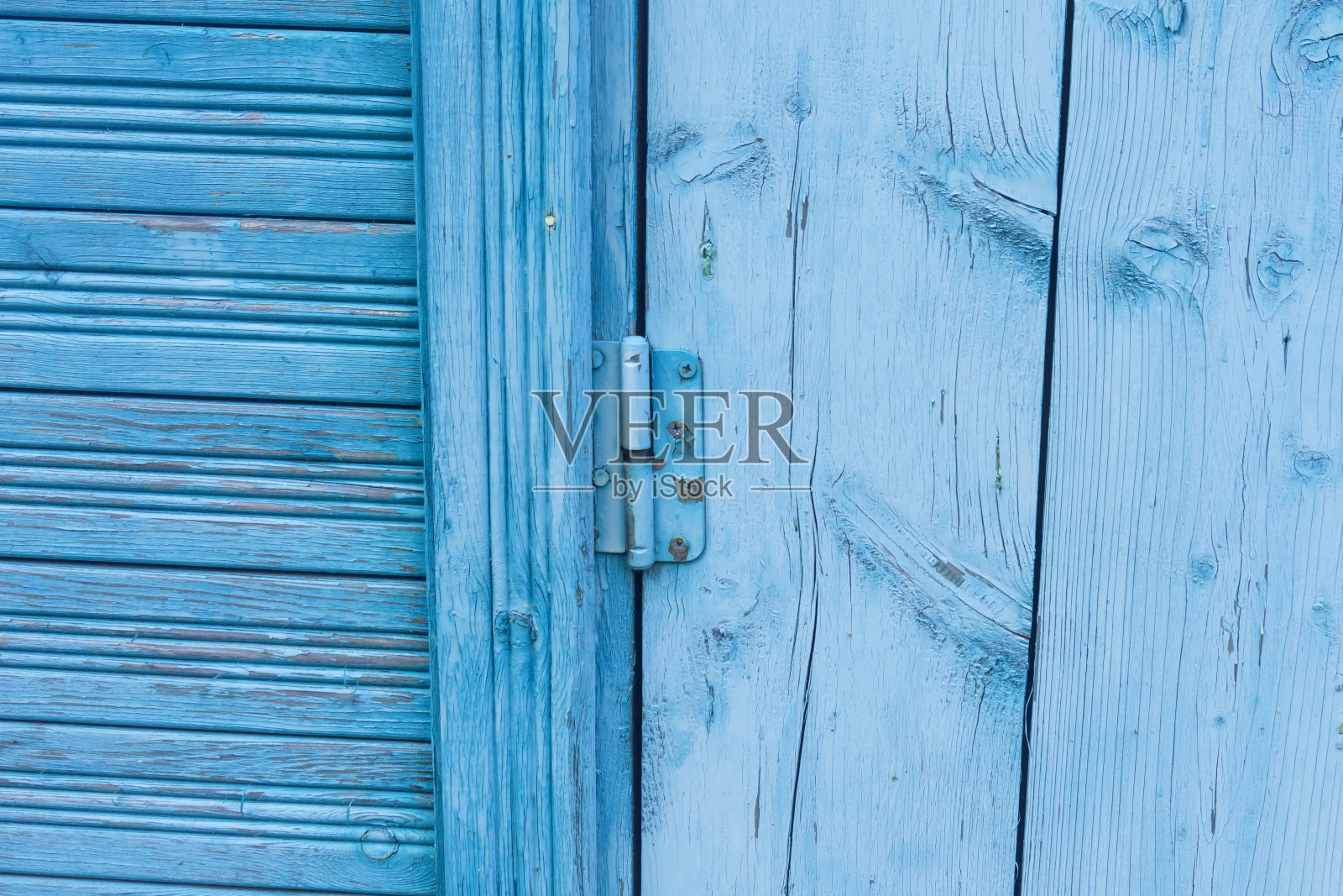 门铰链用螺丝固定在一扇油漆鲜艳的旧木门上照片摄影图片