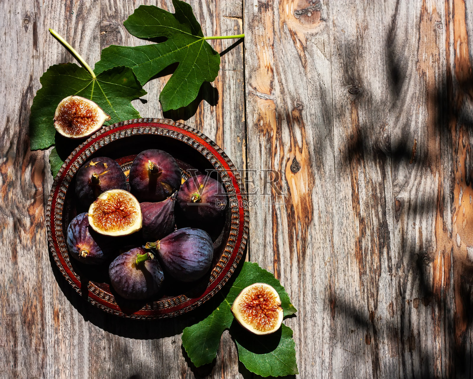 成熟的紫色无花果果实与树叶在木碗木质背景。收获与健康的饮食理念。有选择性的重点。前视图。照片摄影图片