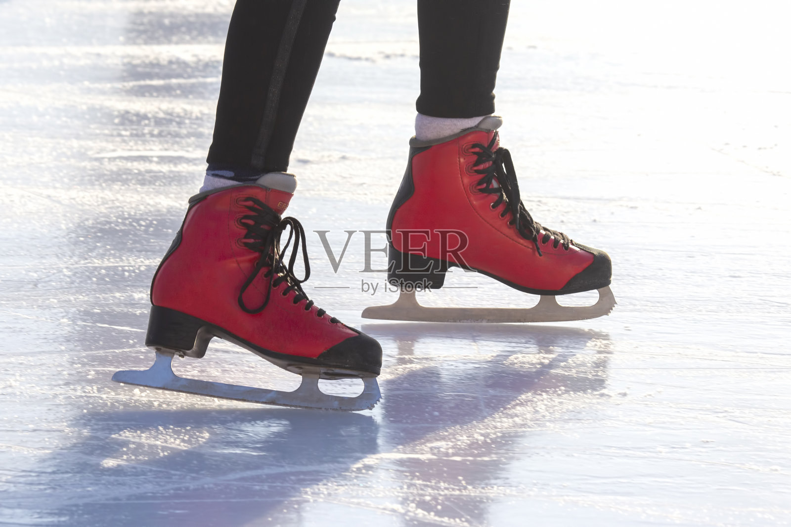 穿着红色溜冰鞋的脚在溜冰场上。爱好和休闲。冬季运动照片摄影图片