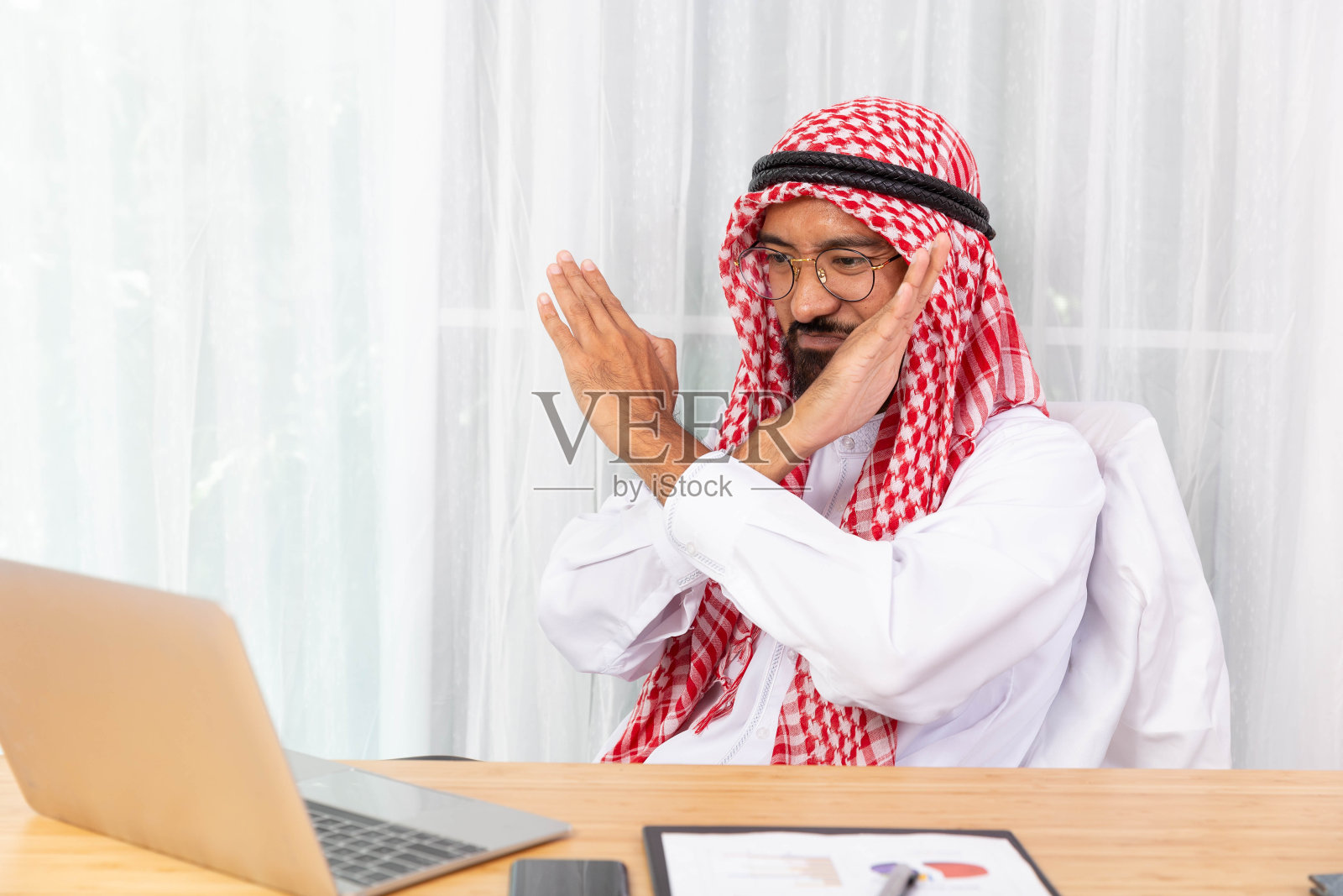 阿拉伯商人感到失望，说不，而与他的商业伙伴通过视频会议在他的办公室笔记本照片摄影图片