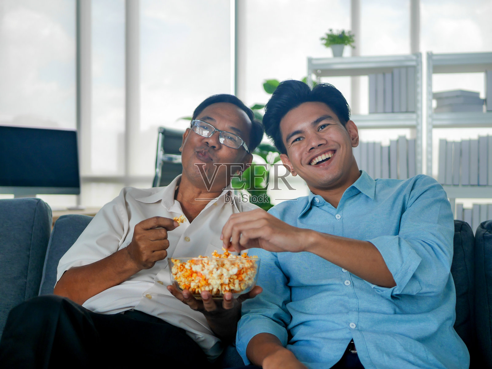 一位年长的亚洲父亲在假期和小儿子一起看电影玩游戏照片摄影图片