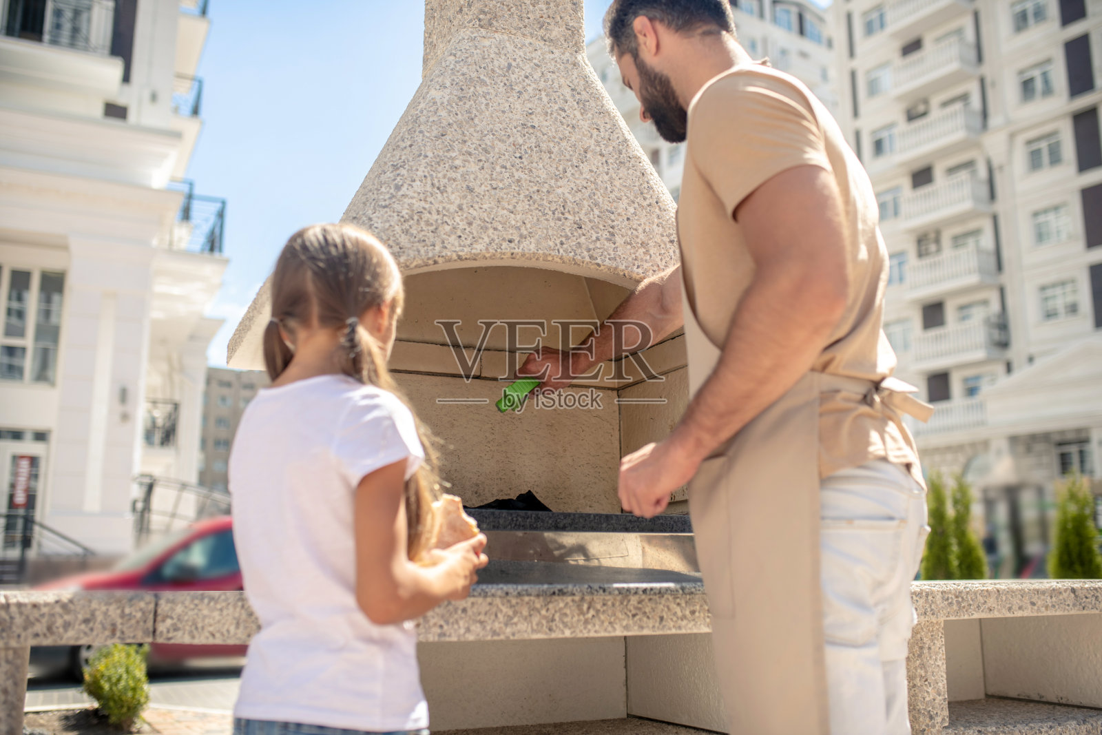 漂亮女孩看着她爸爸烤肉照片摄影图片