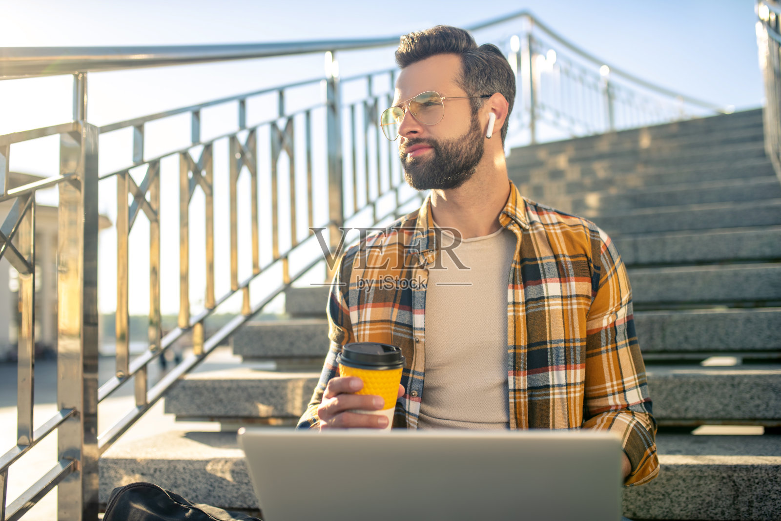 戴耳机的男人在街上喝咖啡照片摄影图片
