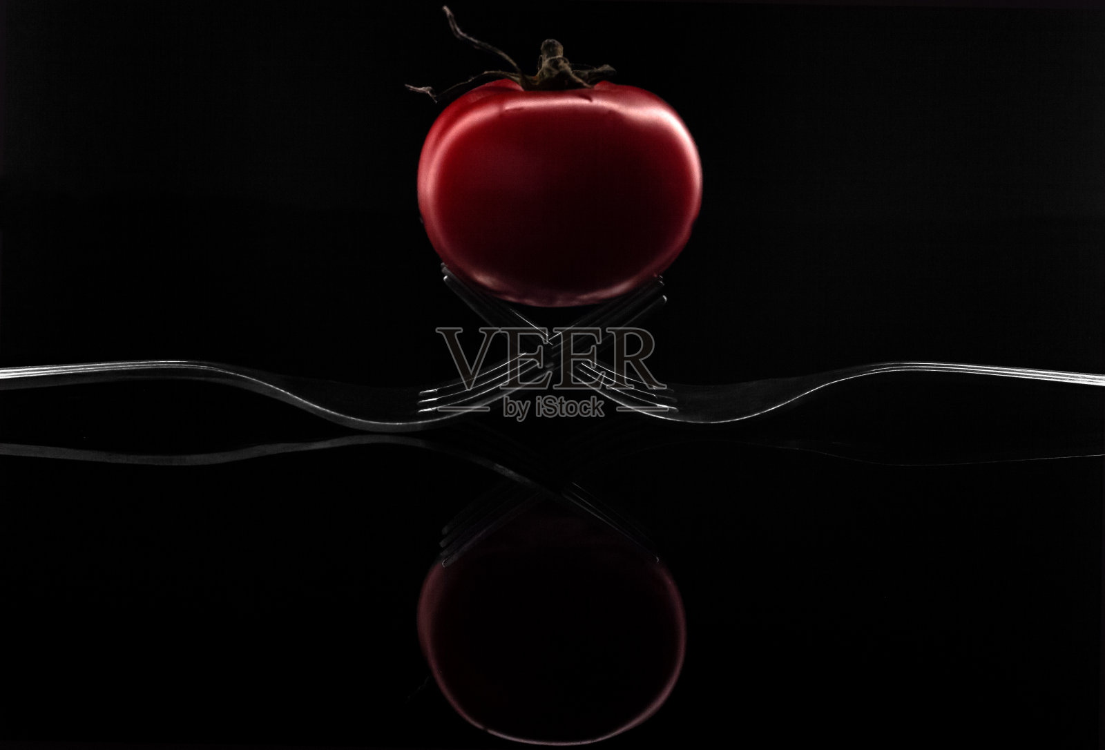 两个叉子和一个在黑色背景上孤立的红樱桃番茄的创意组合照片摄影图片