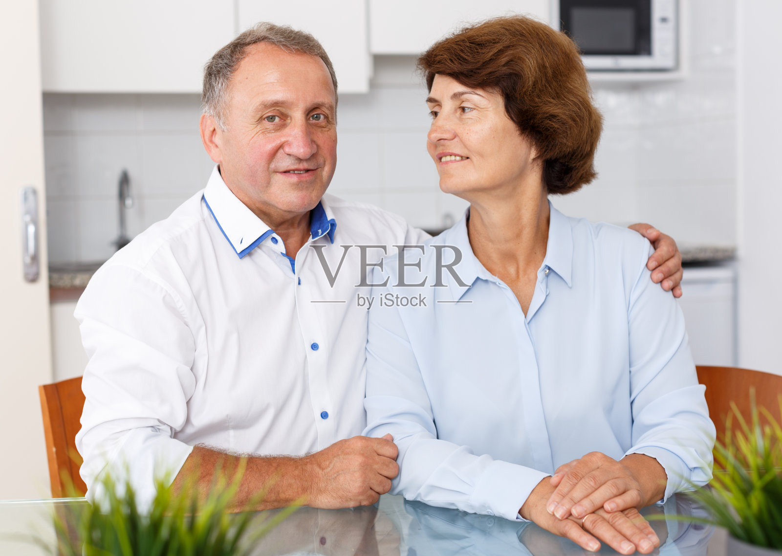 积极成熟的夫妇坐在餐桌上的家庭厨房的肖像照片摄影图片