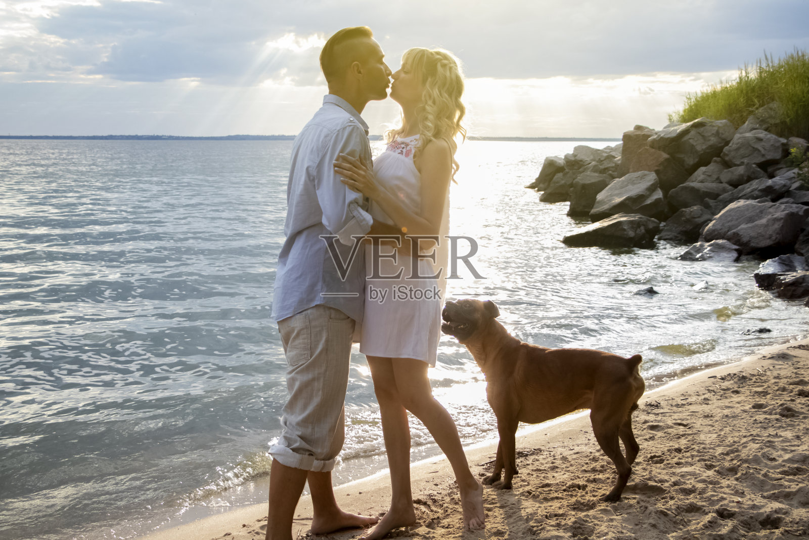 一对情侣躺在沙滩上，旁边是他们的狗。露营和宠物。对彼此和动物的爱情观照片摄影图片