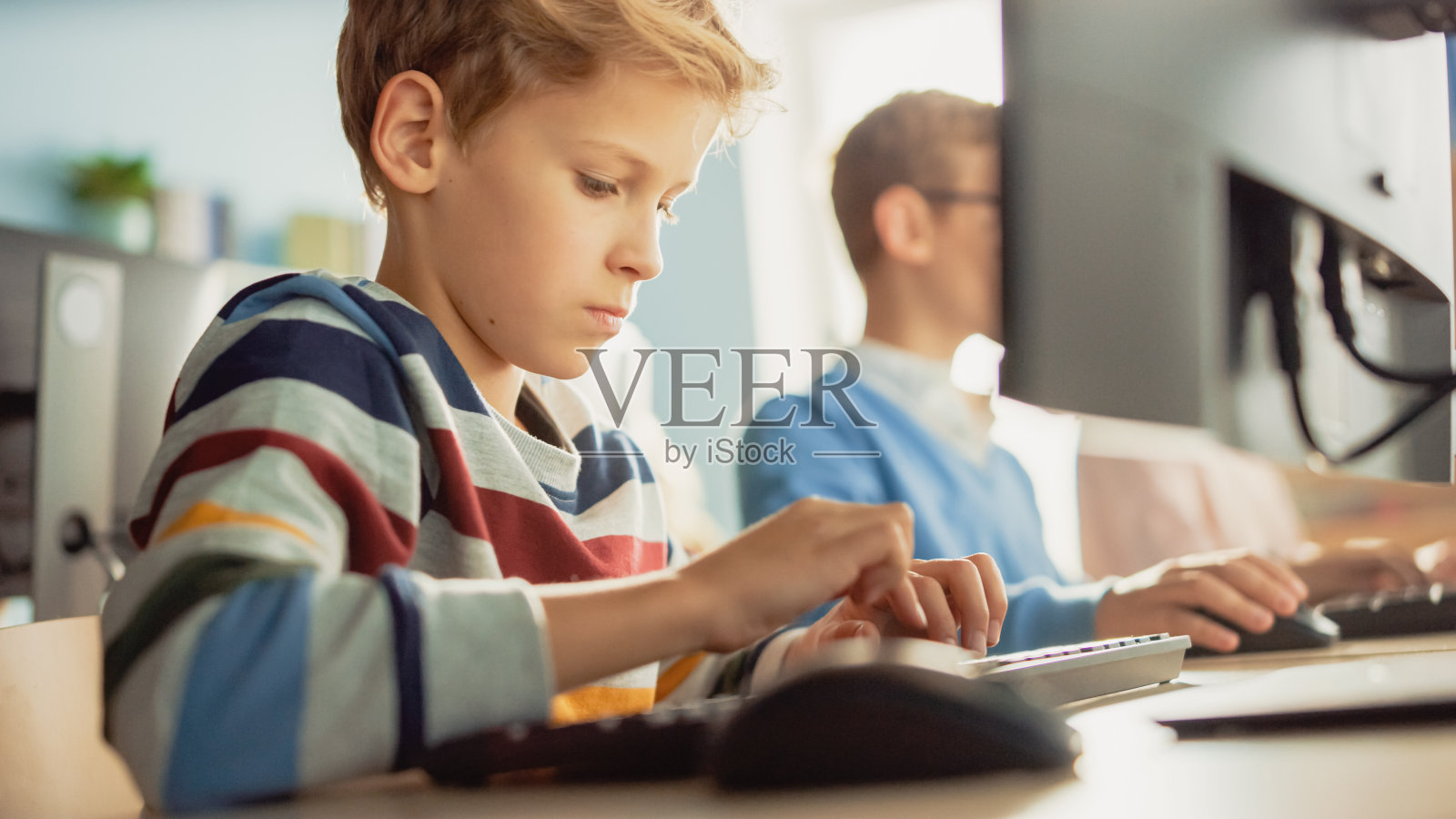 小学计算机科学课堂:聪明的小男孩使用个人电脑，学习如何安全地使用互联网，软件编程语言。现代教育。肖像视图照片摄影图片