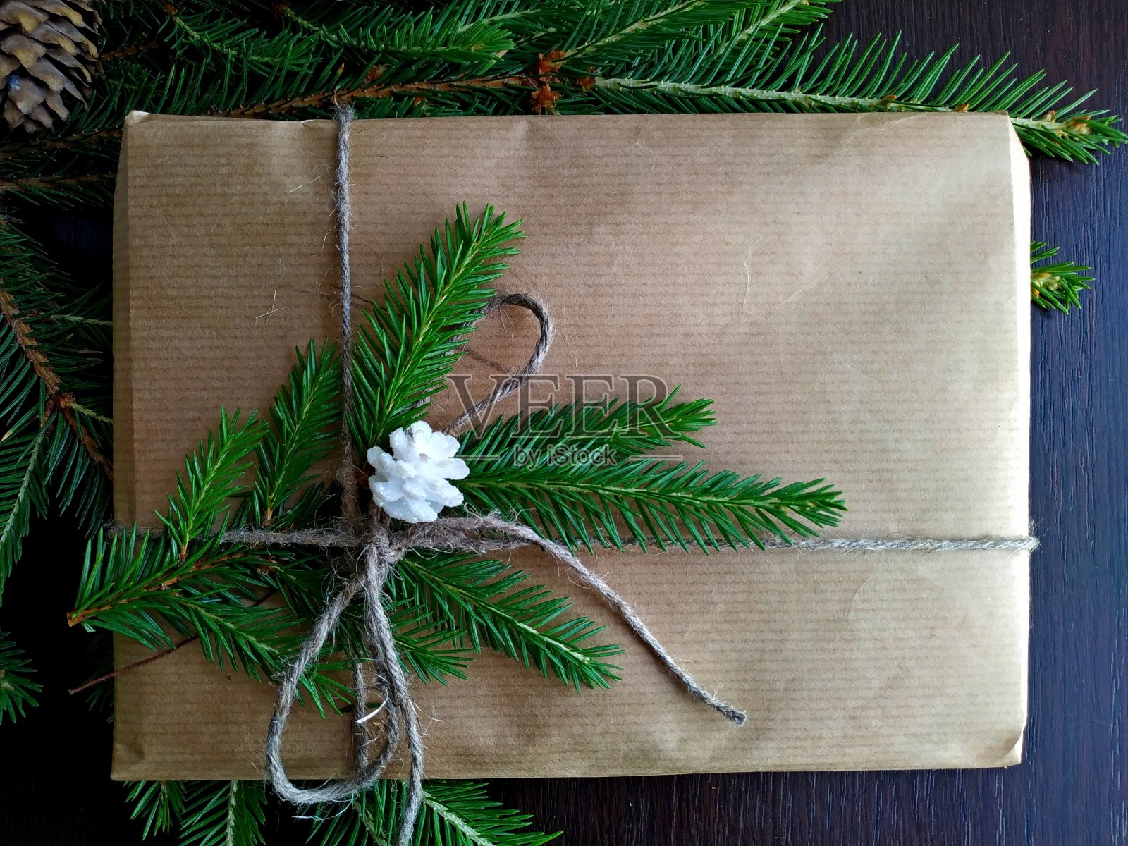 用牛皮纸包着的圣诞礼物放在冷杉树枝上照片摄影图片