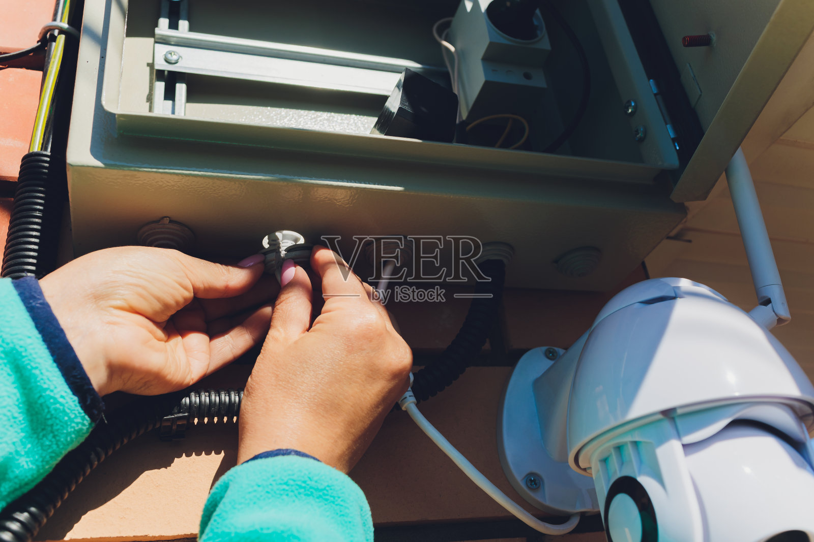 女技术员在墙上安装闭路电视摄像头。照片摄影图片