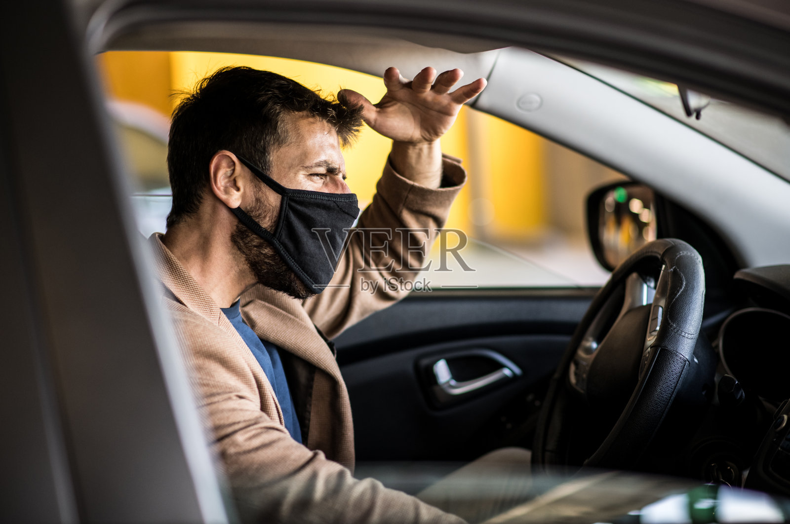 一个年轻人开着一辆戴着口罩的车，遇到交通堵塞，生活在病毒引起的流行病期间照片摄影图片