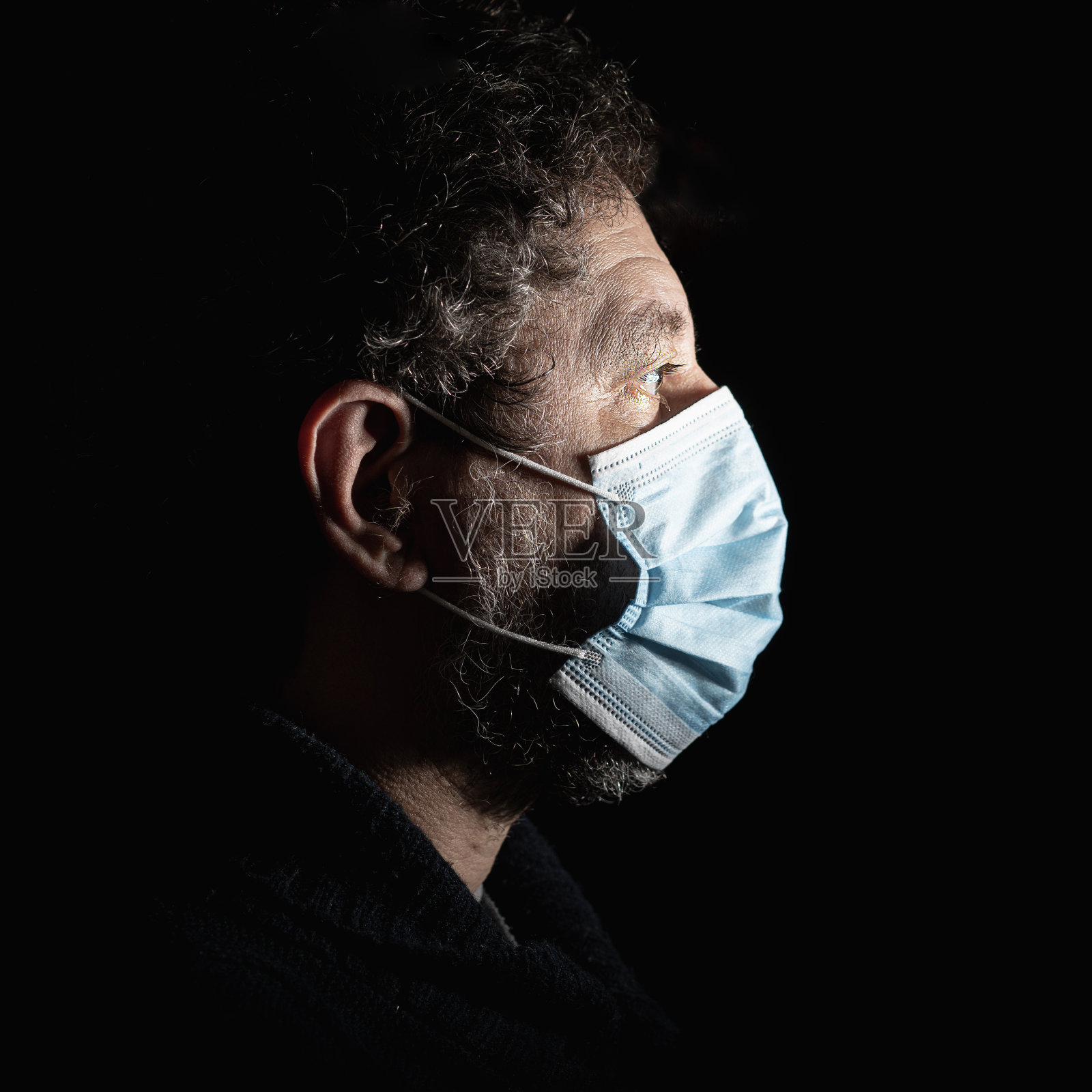 一名成年男性戴着外科口罩以保护自己免受冠状病毒感染。照片摄影图片