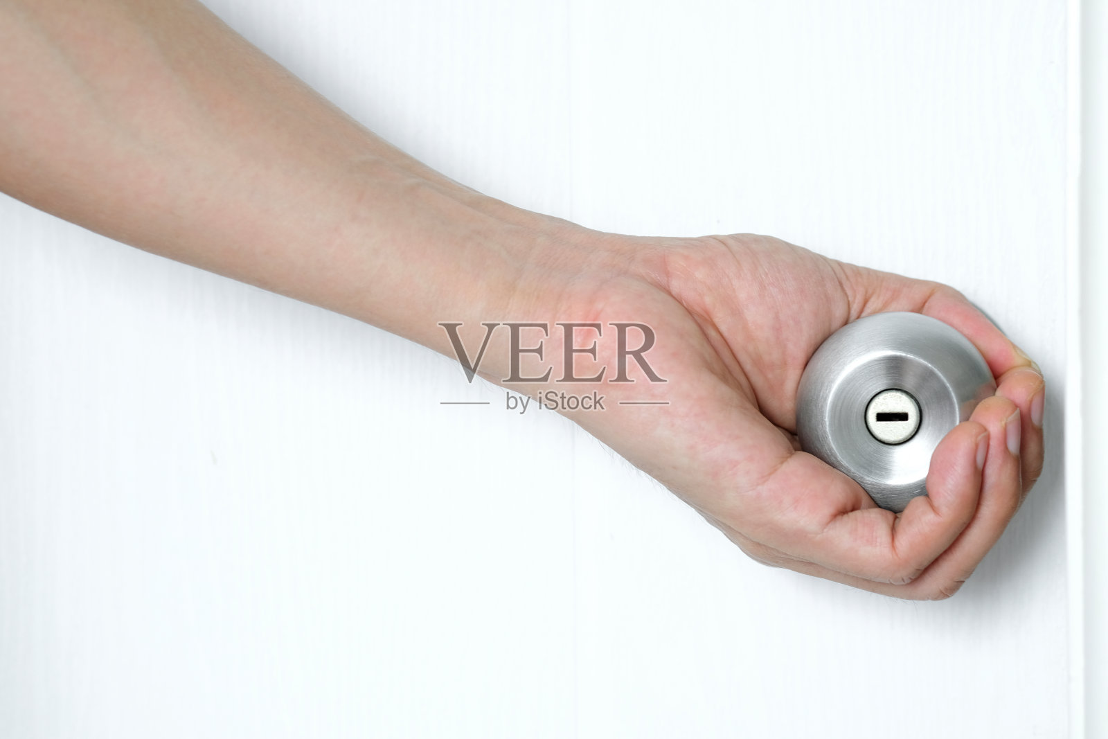 男子的手打开现代白色的门与铬金属钥匙打开房间的门。照片摄影图片