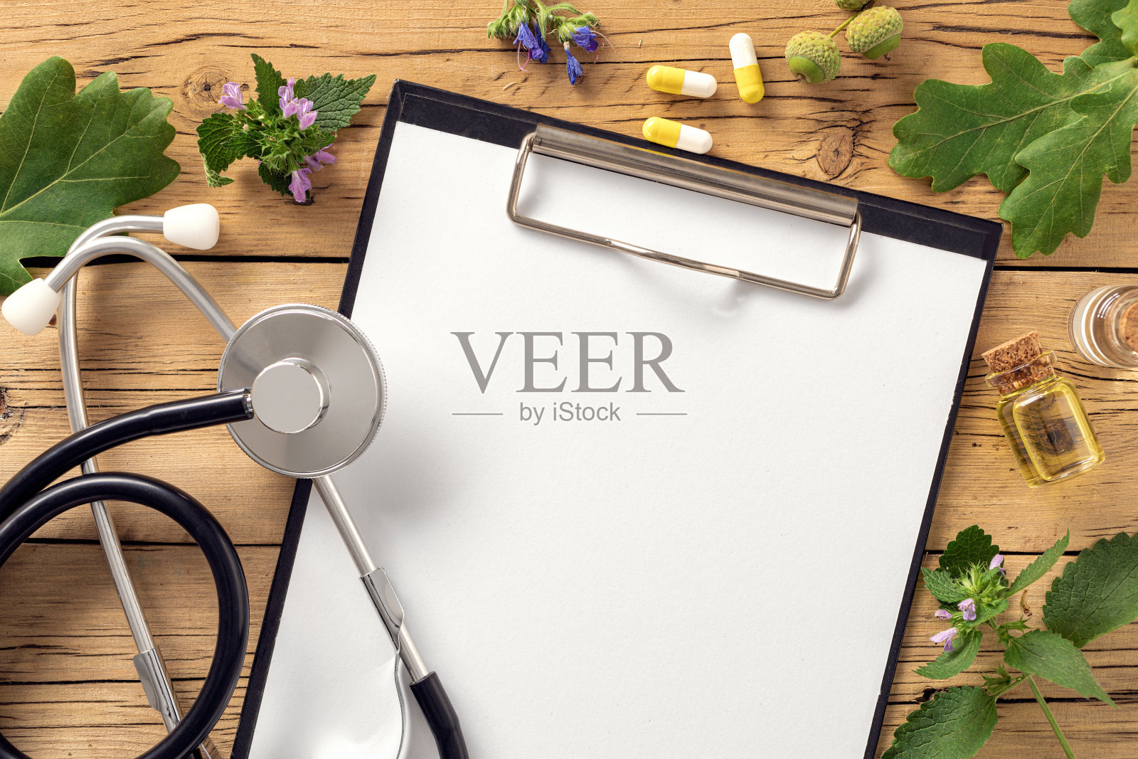 替代医学夹板与听诊器各种植物叶子治疗药草胶囊和健康油在木制桌子上俯视图照片摄影图片